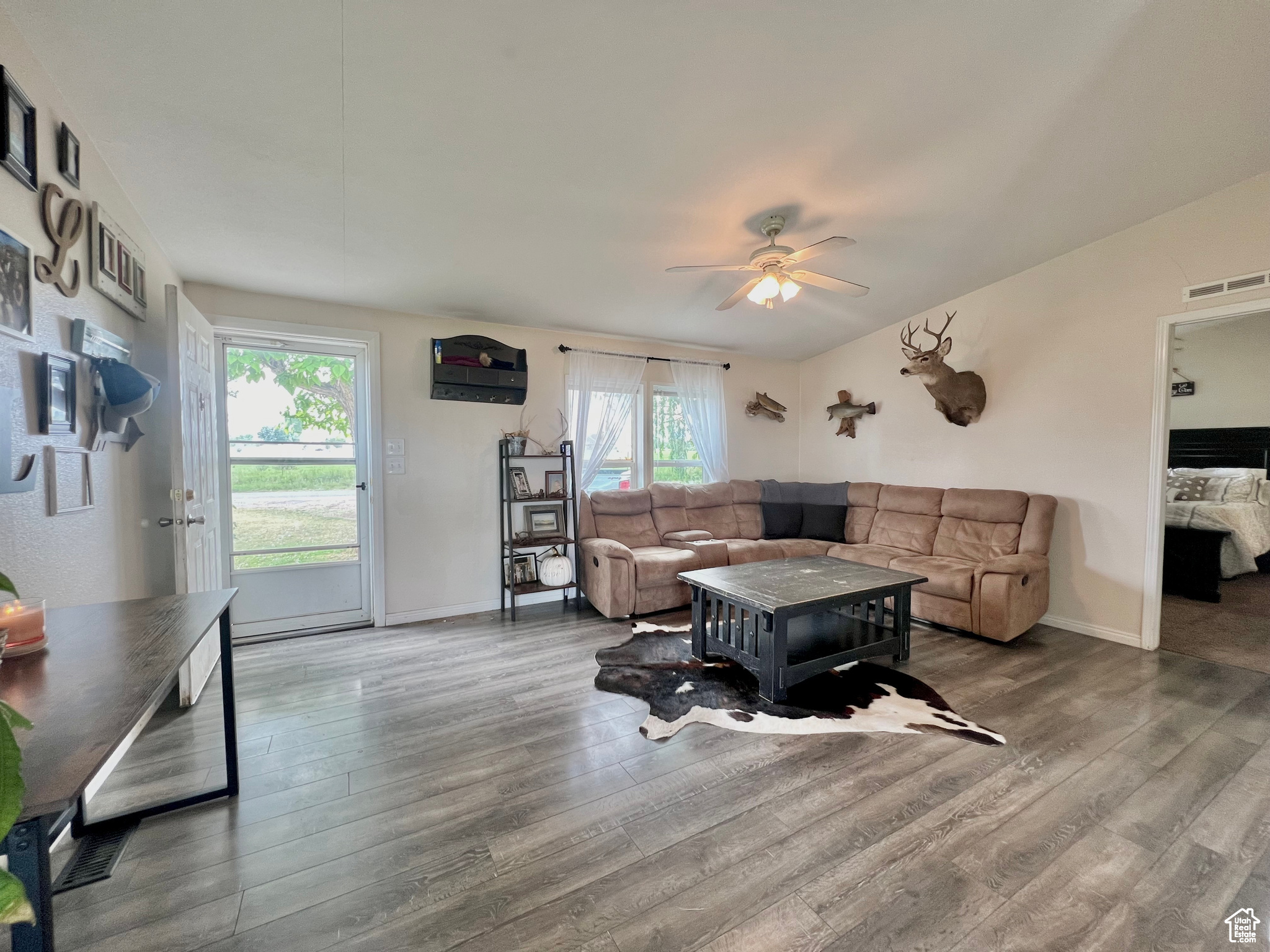 Living room featuring visible vents, baseboards, ceiling fan, and wood finished floors