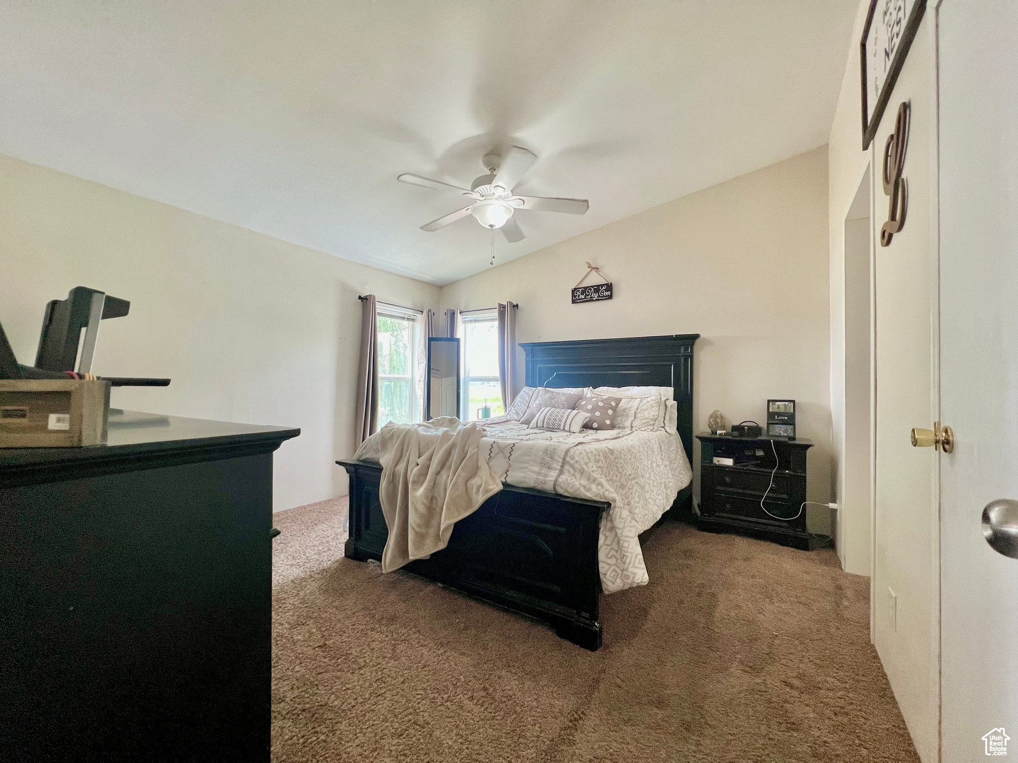 Carpeted bedroom featuring ceiling fan and vaulted ceiling