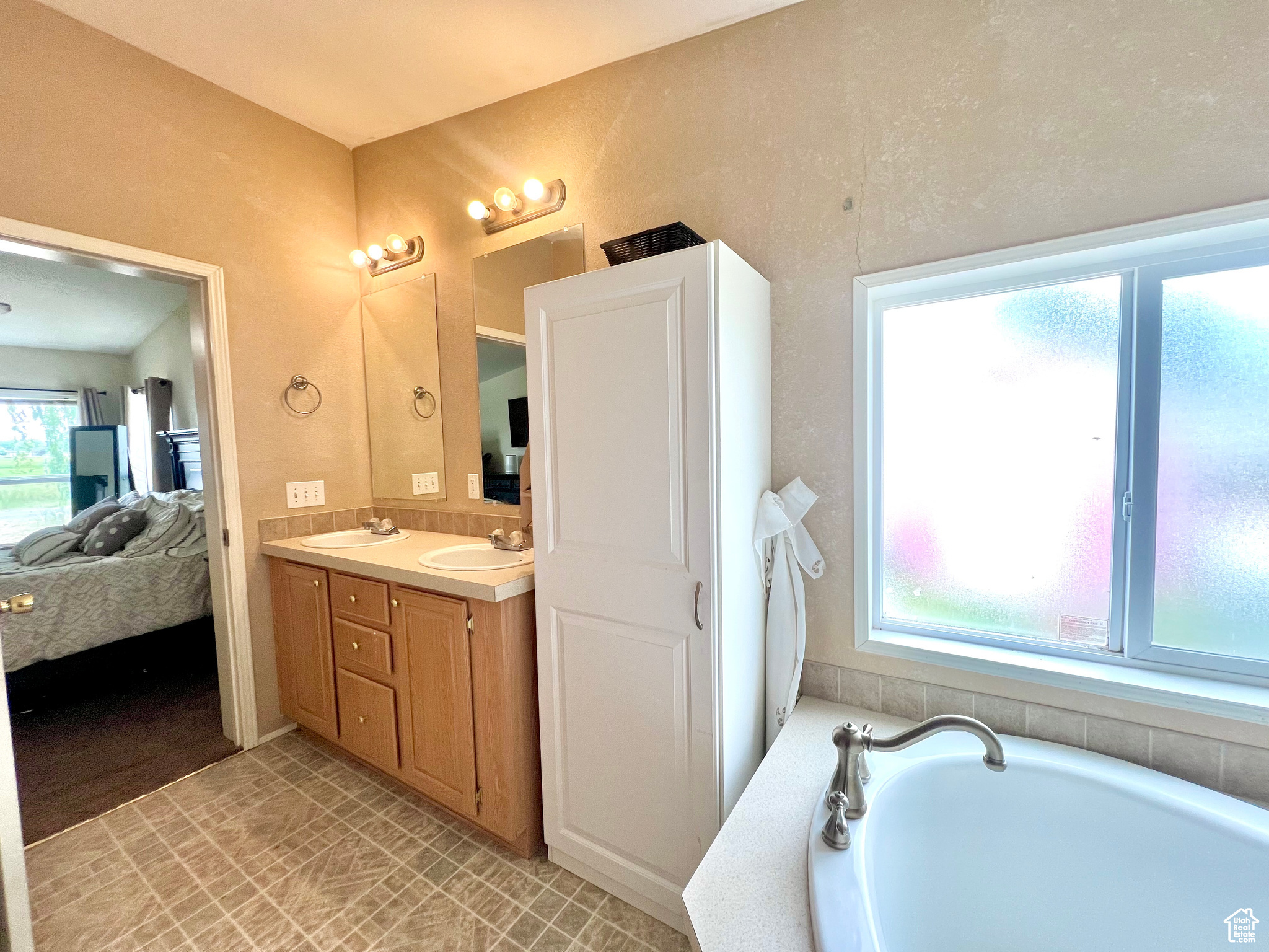 Full bath featuring a bath, double vanity, ensuite bathroom, and a sink