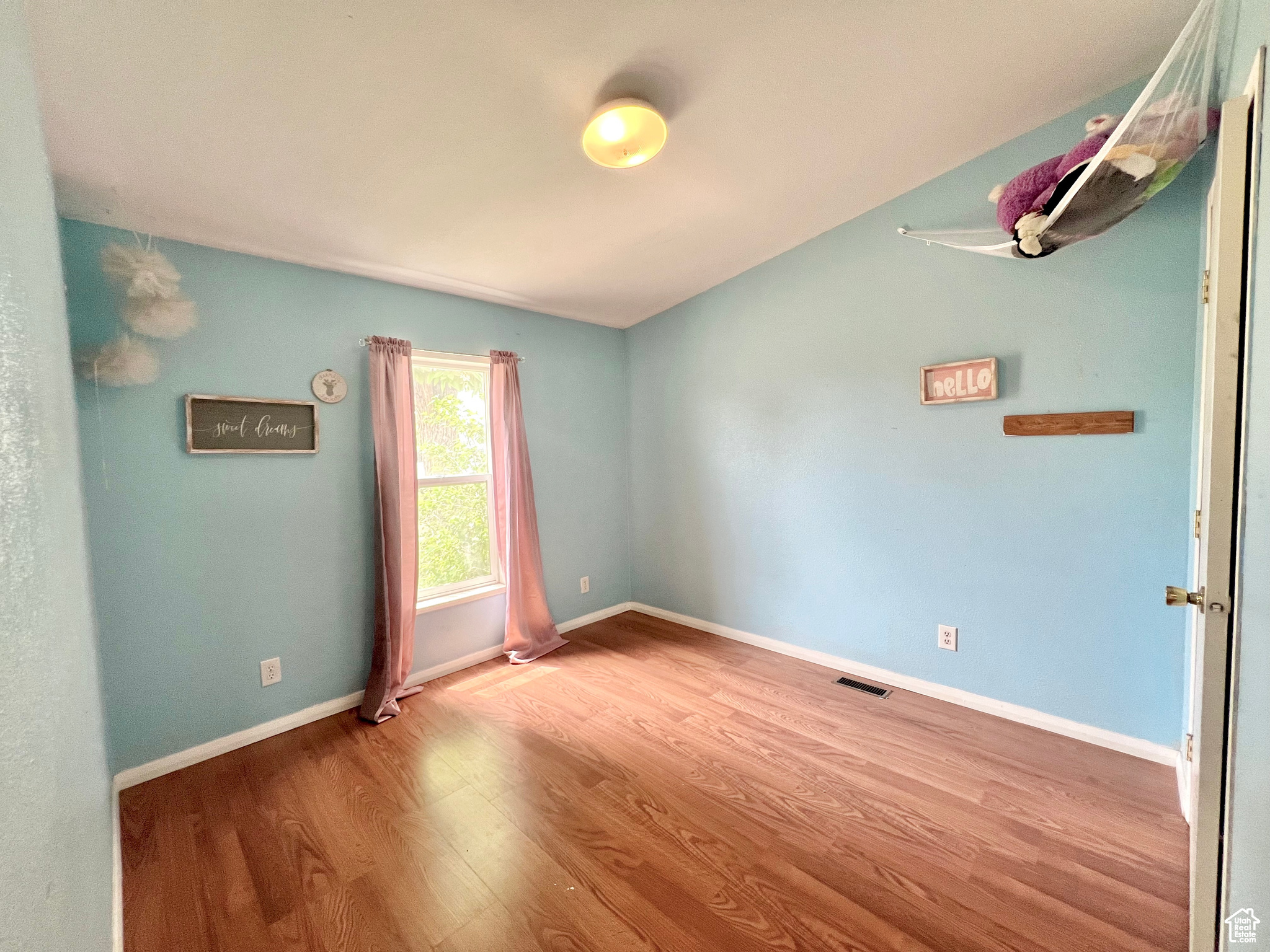 Empty room featuring visible vents, baseboards, and wood finished floors