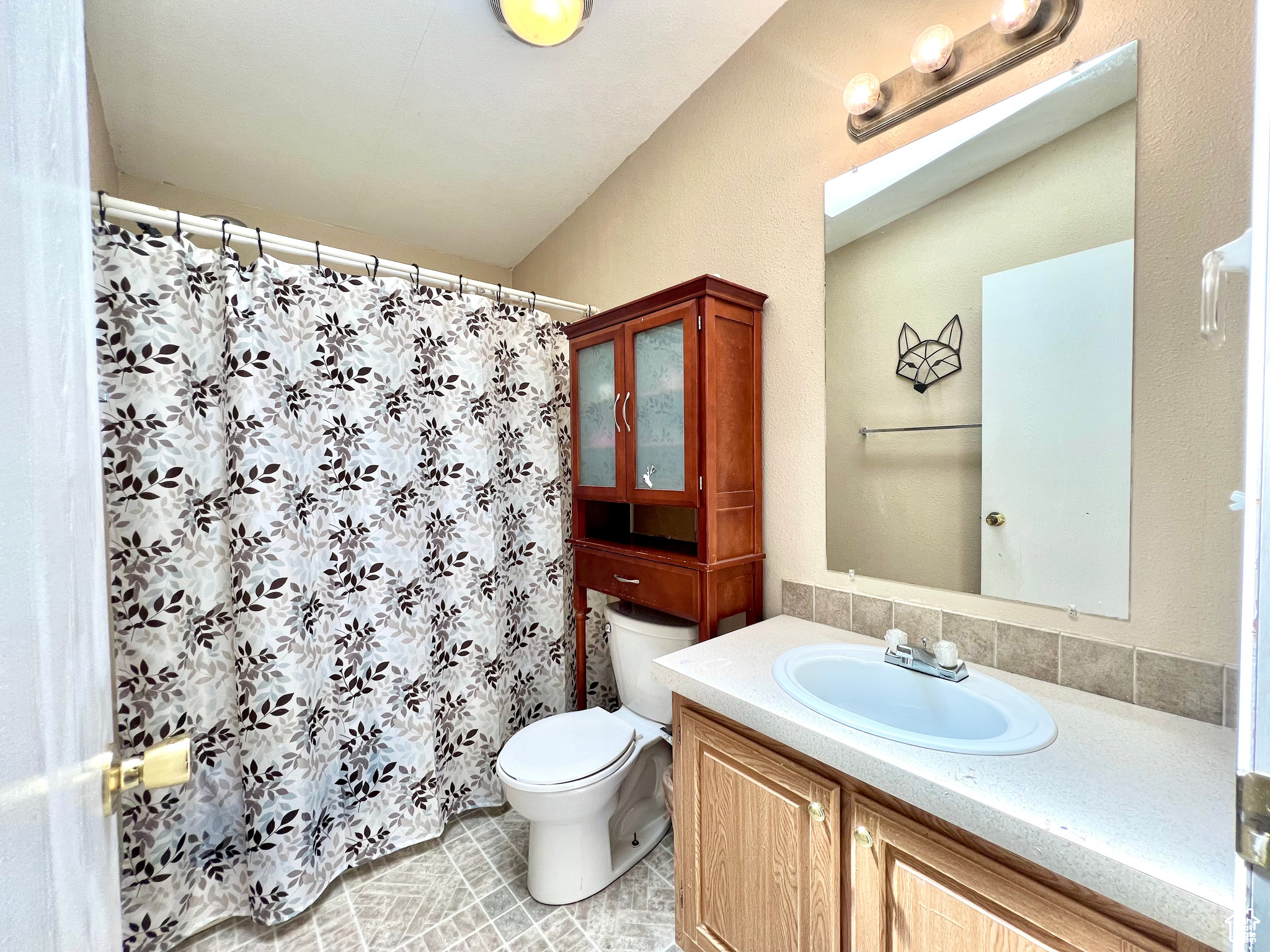 Bathroom featuring a shower with shower curtain, toilet, and vanity