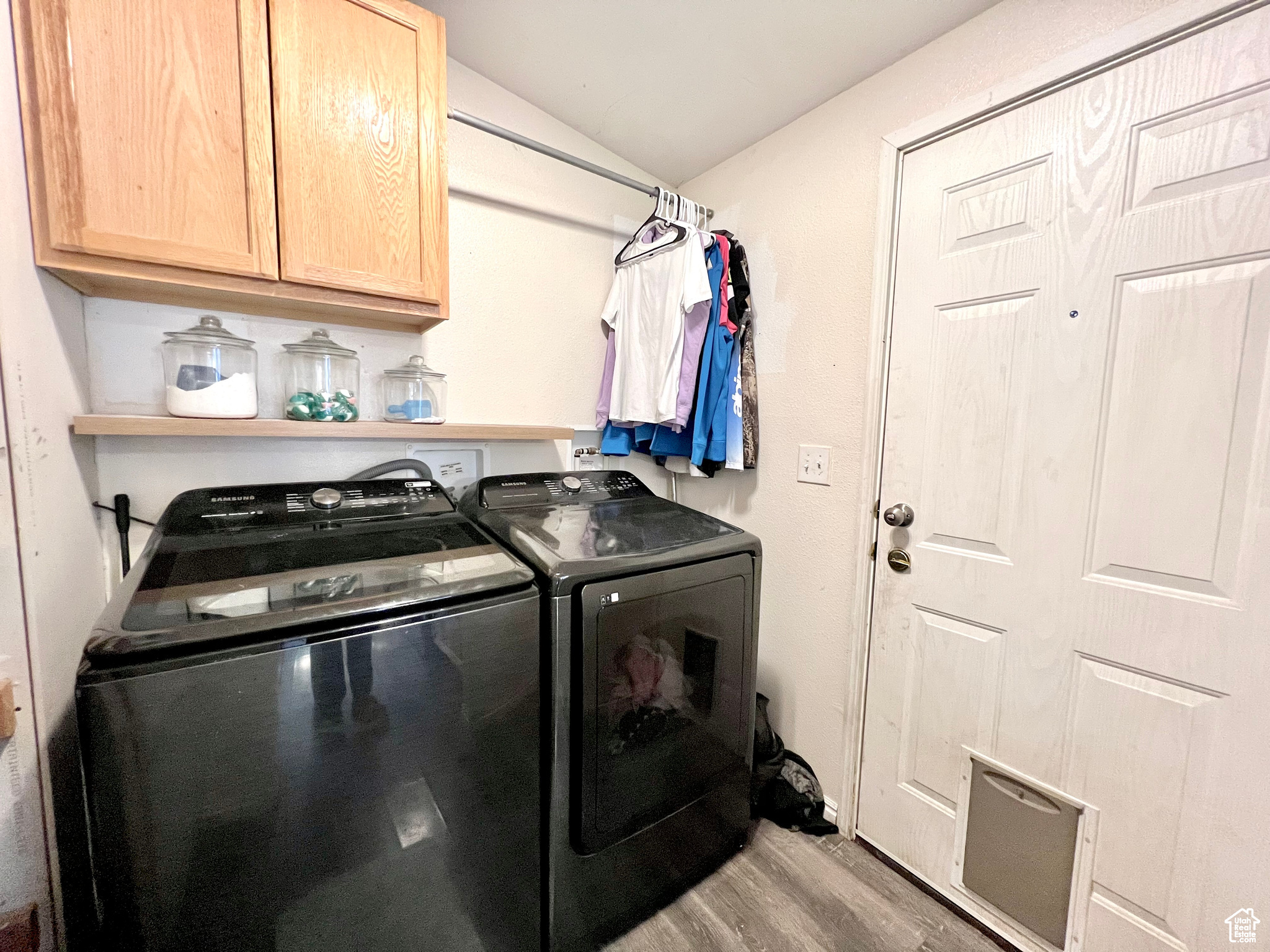 Laundry room featuring cabinet space, wood finished floors, and separate washer and dryer