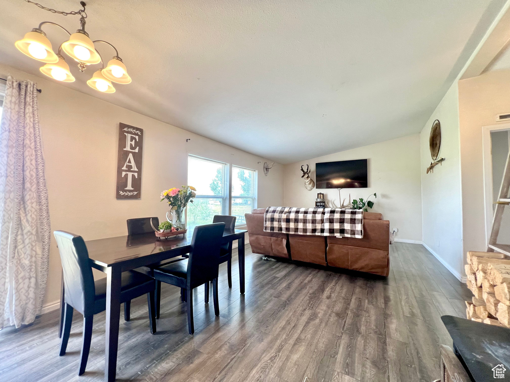 Dining room with vaulted ceiling, a notable chandelier, wood finished floors, and baseboards