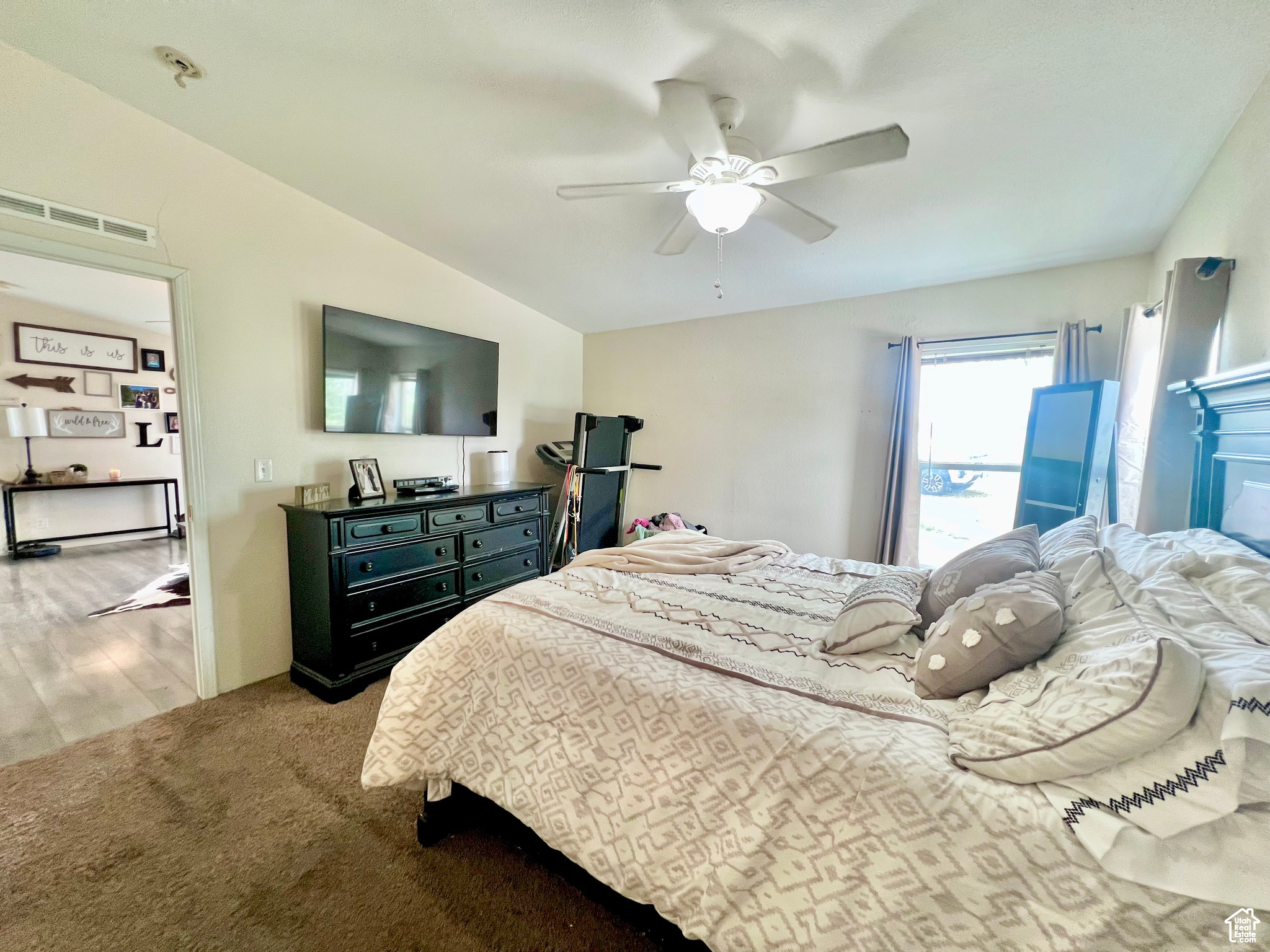 Carpeted bedroom with vaulted ceiling, a ceiling fan, and visible vents