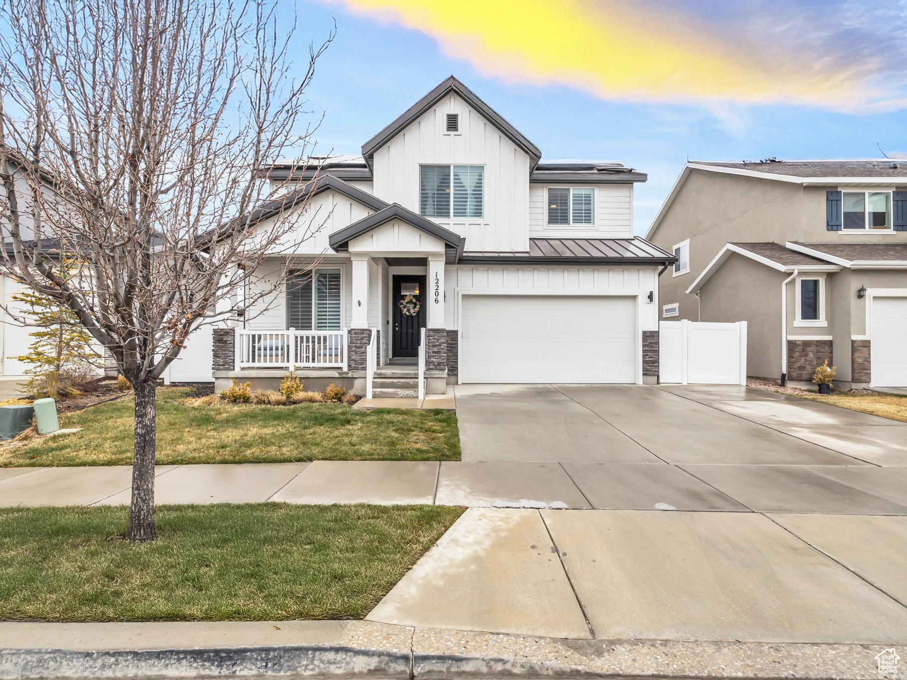 View of front facade with driveway, an attached garage, covered porch, roof mounted solar panels, and metal roof
