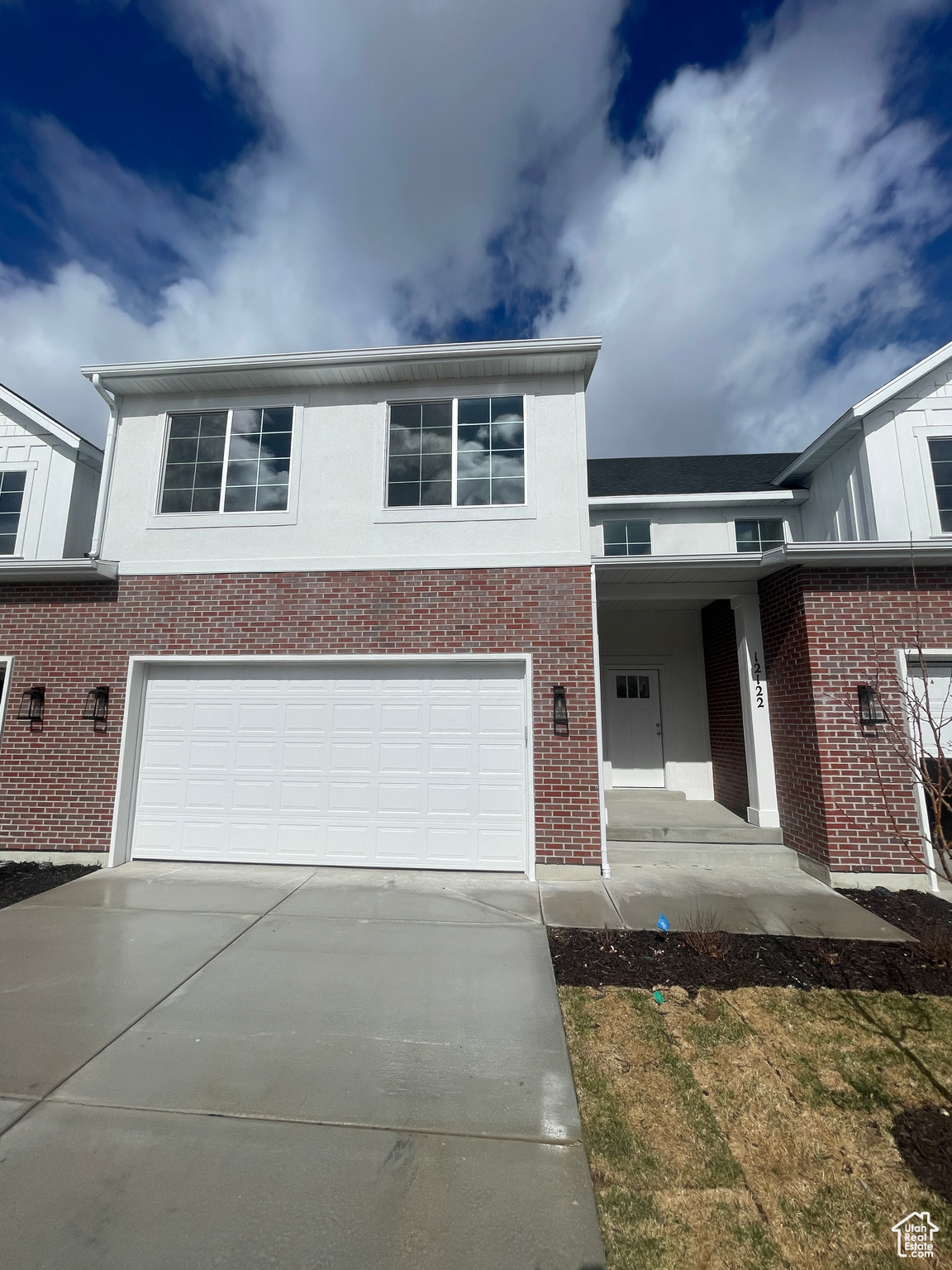 View of front of property with brick siding, an attached garage, and driveway
