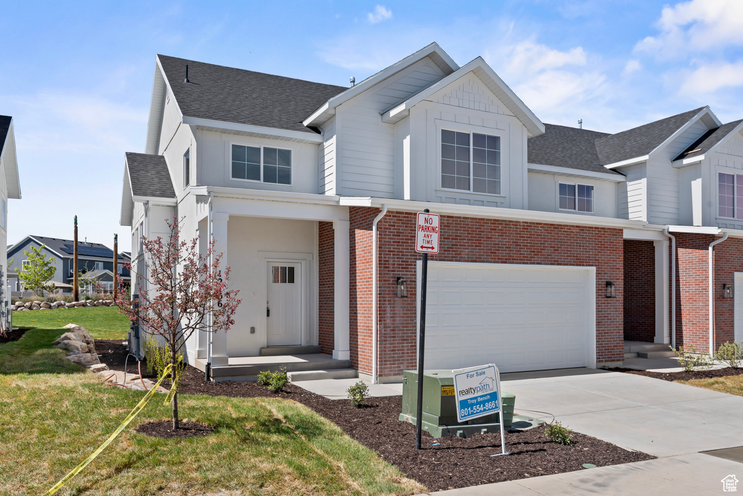 View of front of home with brick siding, a garage, driveway, and roof with shingles