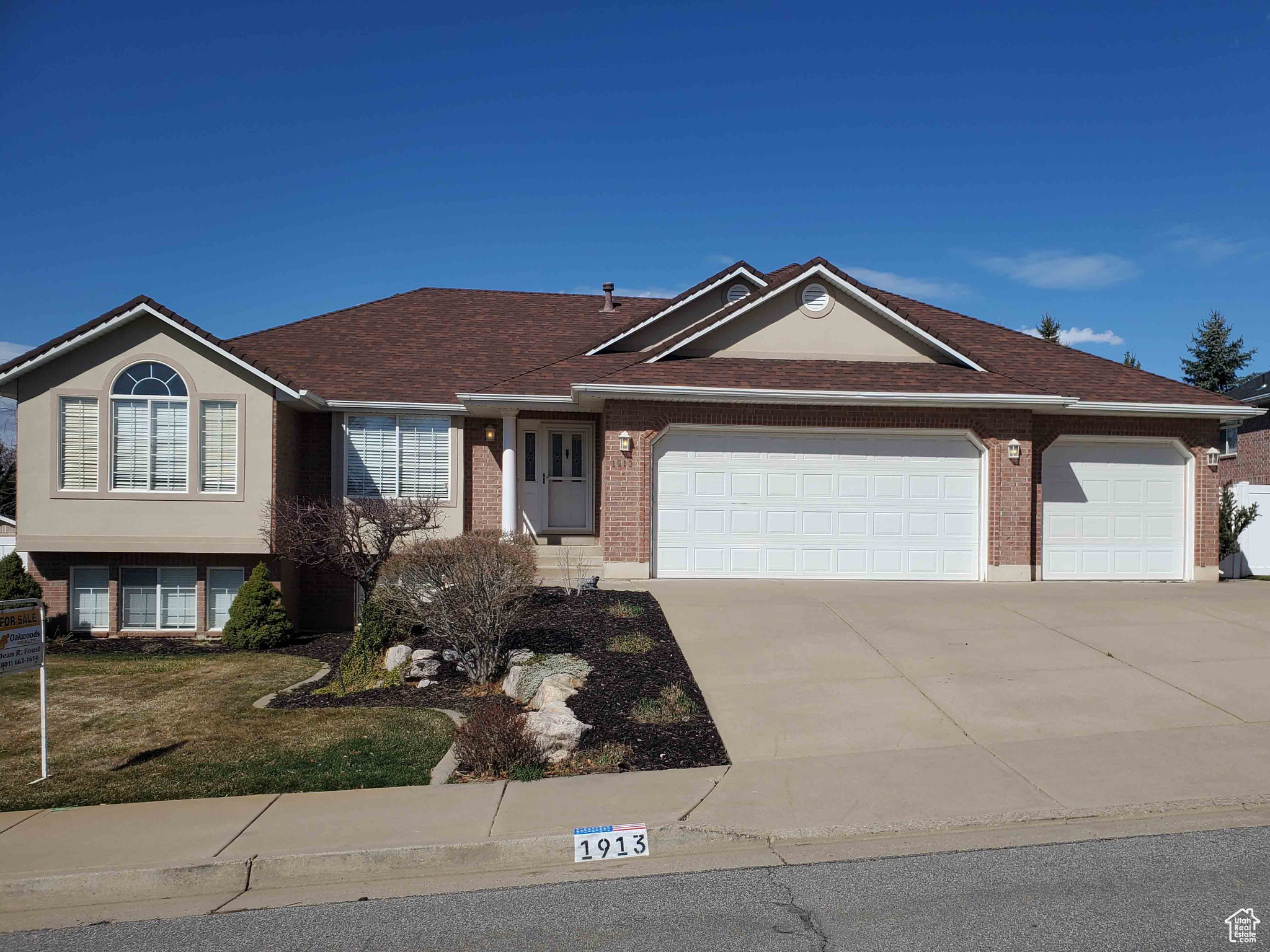 Single story home featuring brick siding, concrete driveway, an attached garage, and a shingled roof