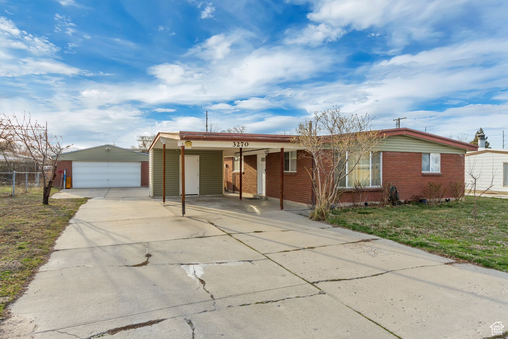 Ranch-style house featuring an outbuilding, a front yard, fence, concrete driveway, and a detached garage