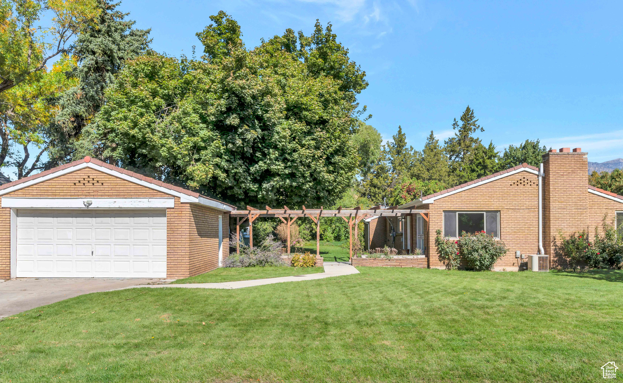 View of yard with a garage, concrete driveway, central AC, and a pergola