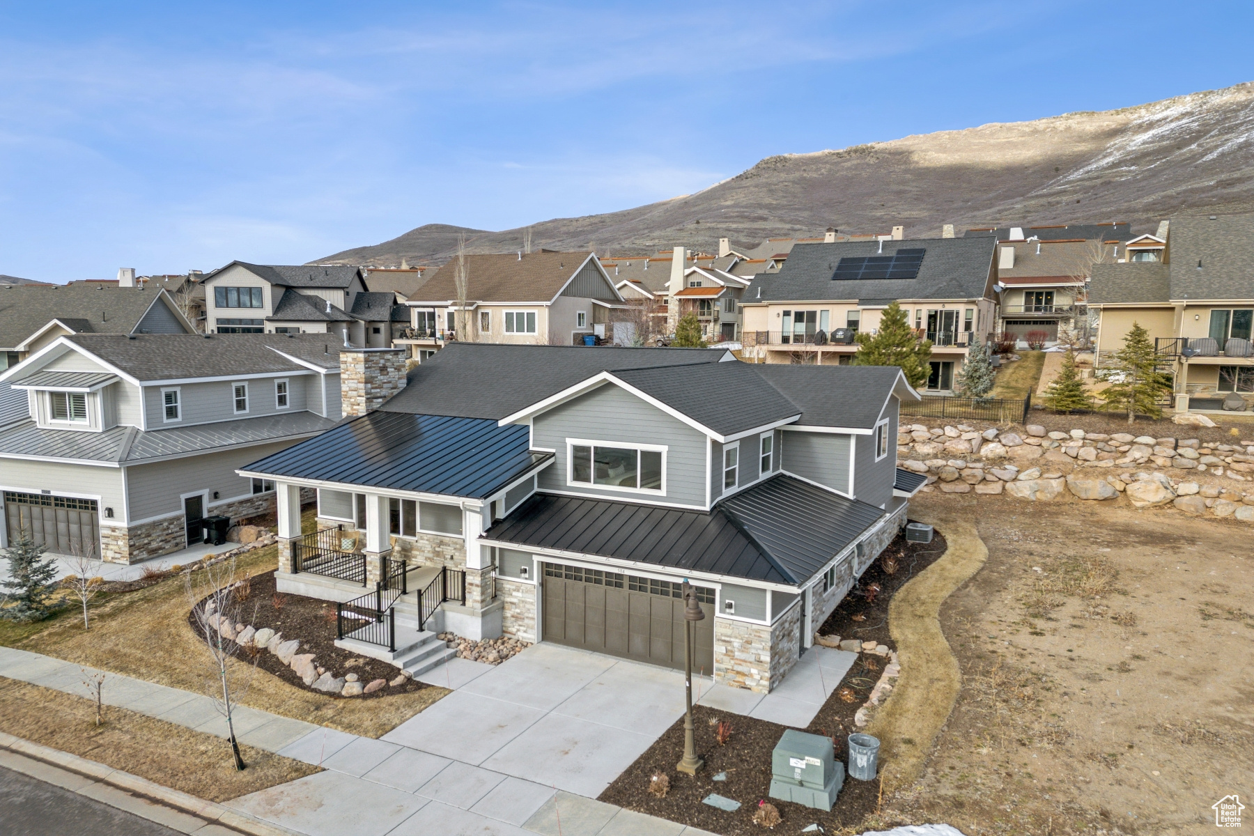 View of front facade featuring a residential view, metal roof, a garage, stone siding, and a standing seam roof