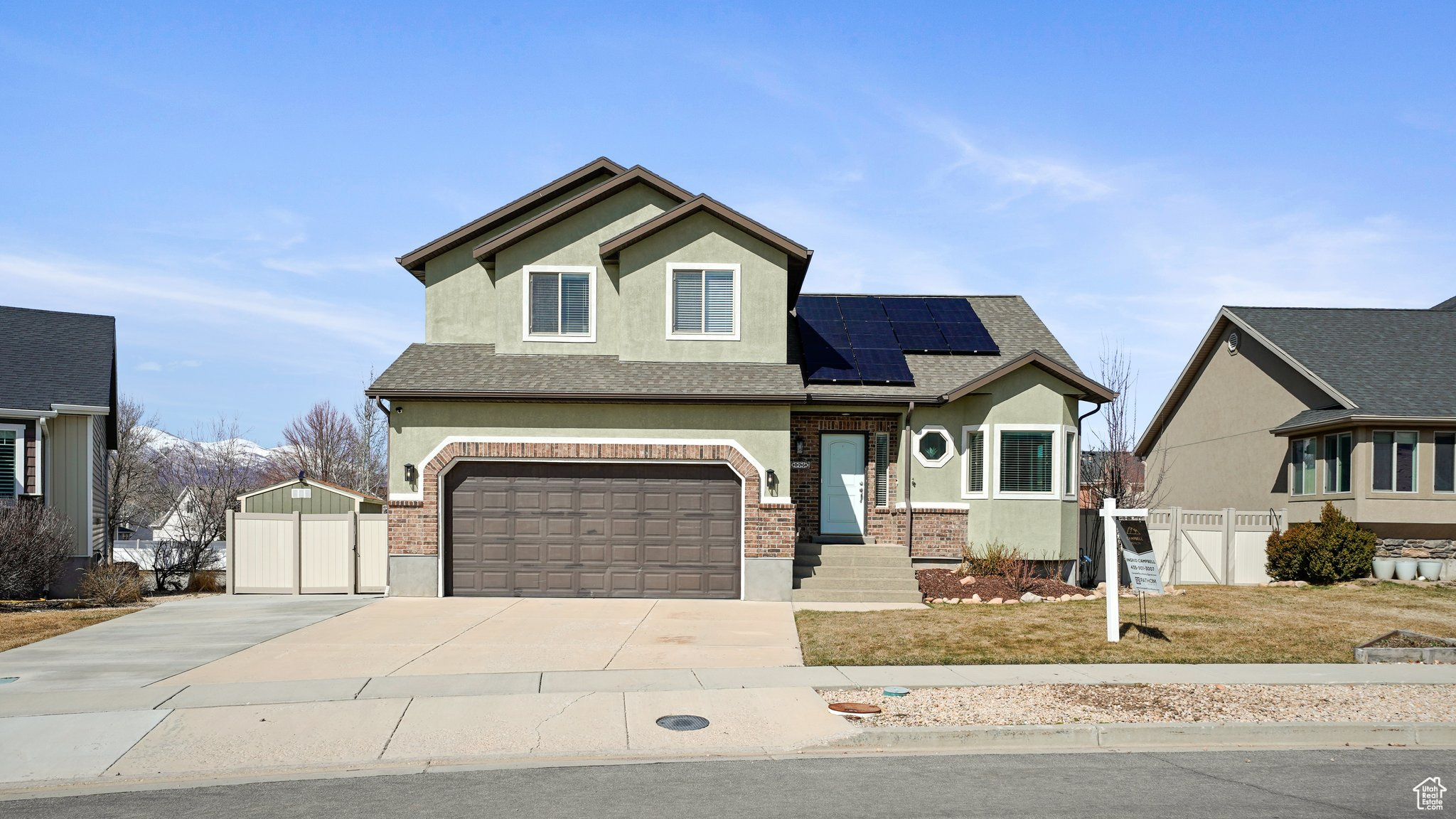 View of front of property with stucco siding, driveway, a gate, roof mounted solar panels, and fence