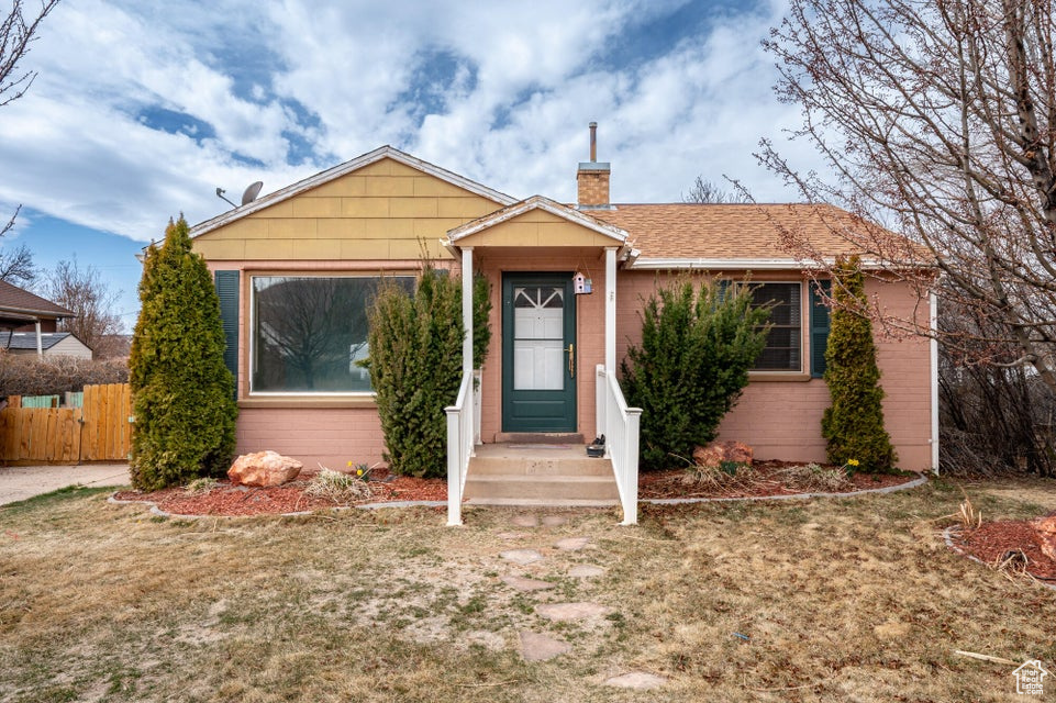 Bungalow-style home with a chimney and fence