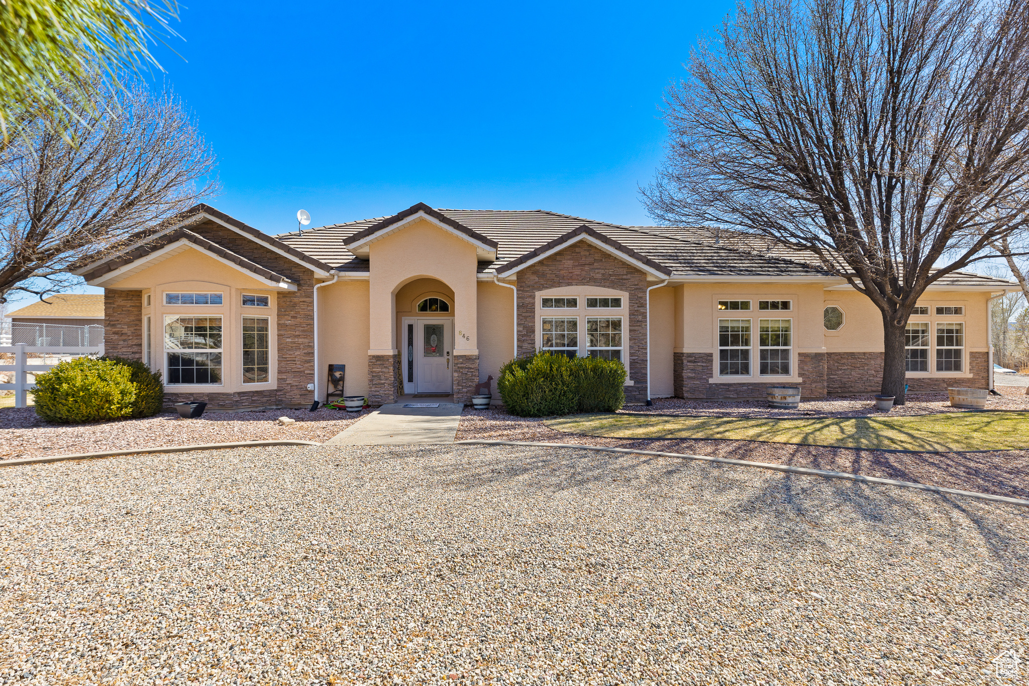 Single story home with stone siding, stucco siding, a tiled roof, and fence