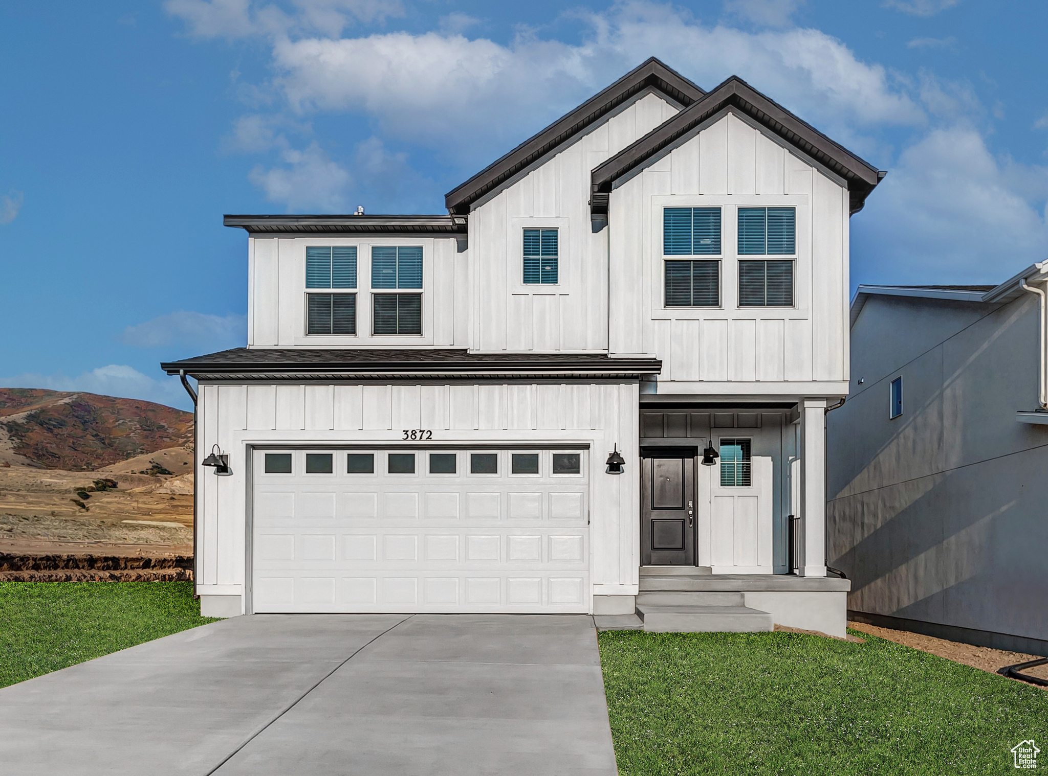 Modern inspired farmhouse featuring driveway, an attached garage, a front lawn, board and batten siding, and a mountain view
