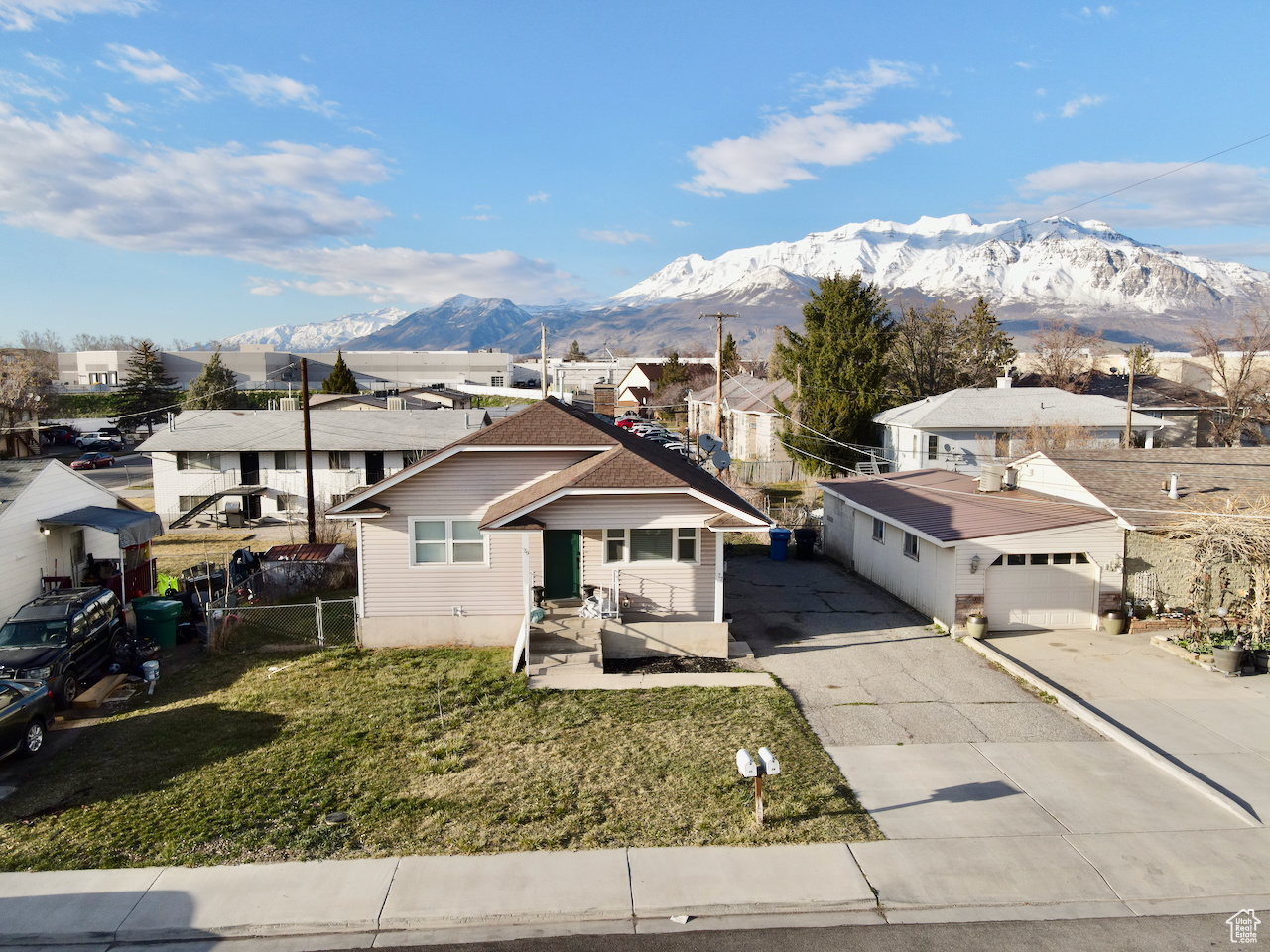 View of front of property featuring fence, a residential view, a front yard, driveway, and a mountain view