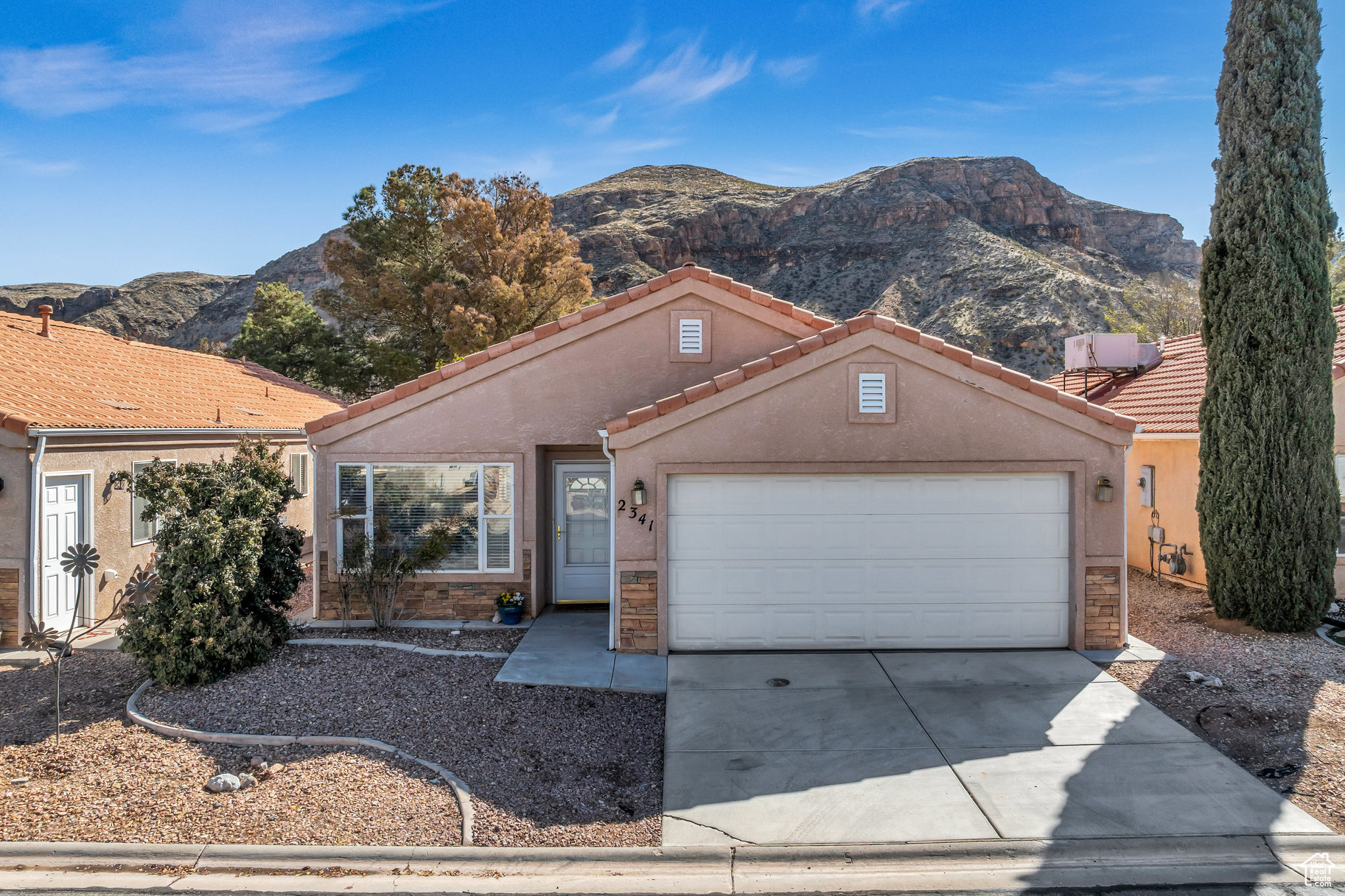 View of front of home featuring an attached garage, a mountain view, driveway, and stucco siding