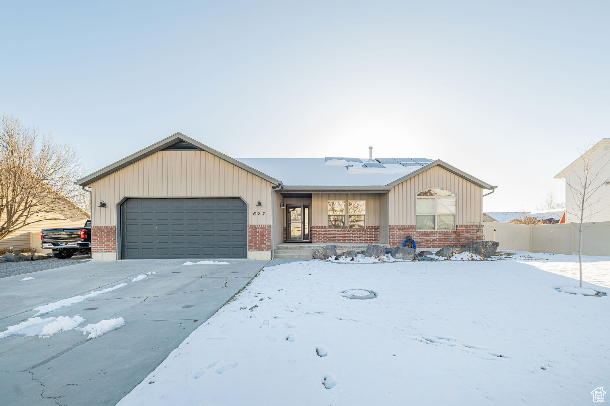 Ranch-style home featuring driveway, brick siding, an attached garage, and fence