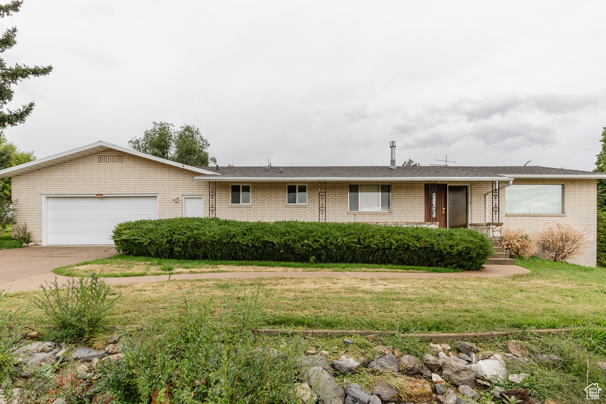 Ranch-style house with brick siding, a garage, concrete driveway, and a front yard