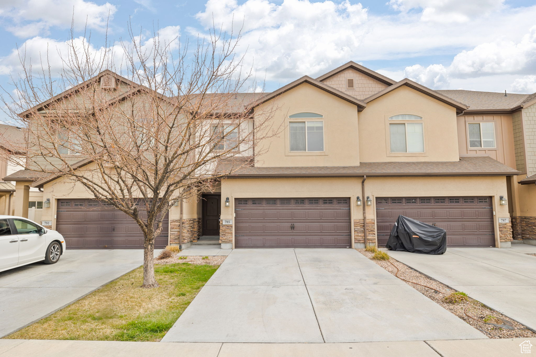 Townhome / multi-family property featuring stucco siding, stone siding, a garage, and concrete driveway