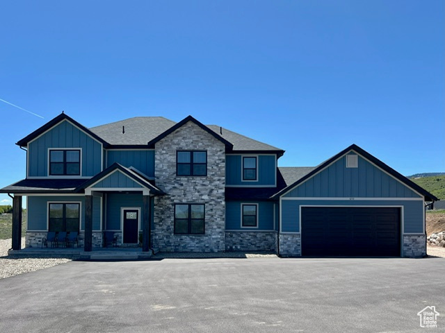 Craftsman house with an attached garage, covered porch, stone siding, and board and batten siding