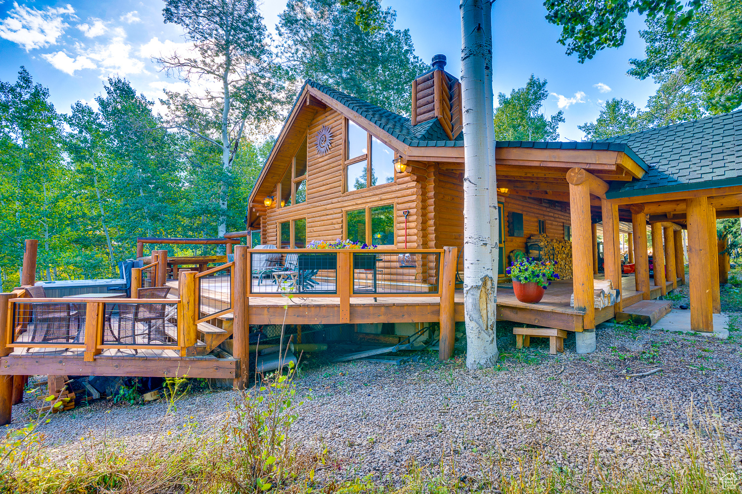 Back of house featuring a chimney, roof with shingles, a wooden deck, and log exterior