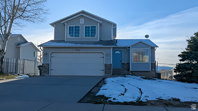 Traditional home featuring fence, driveway, stone siding, and a garage