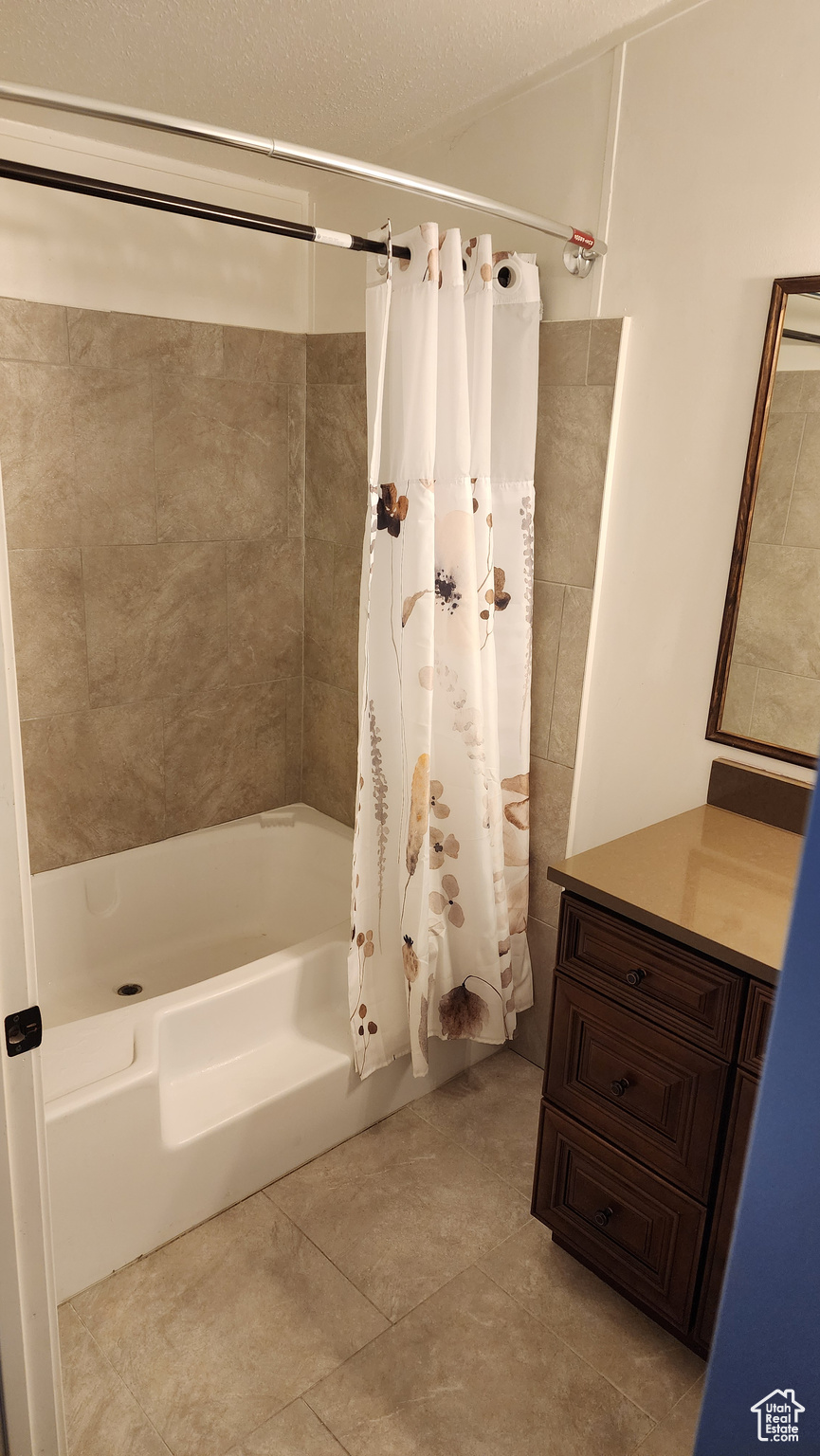 Full bath featuring tile patterned floors, a textured ceiling, vanity, and shower / bath combination with curtain