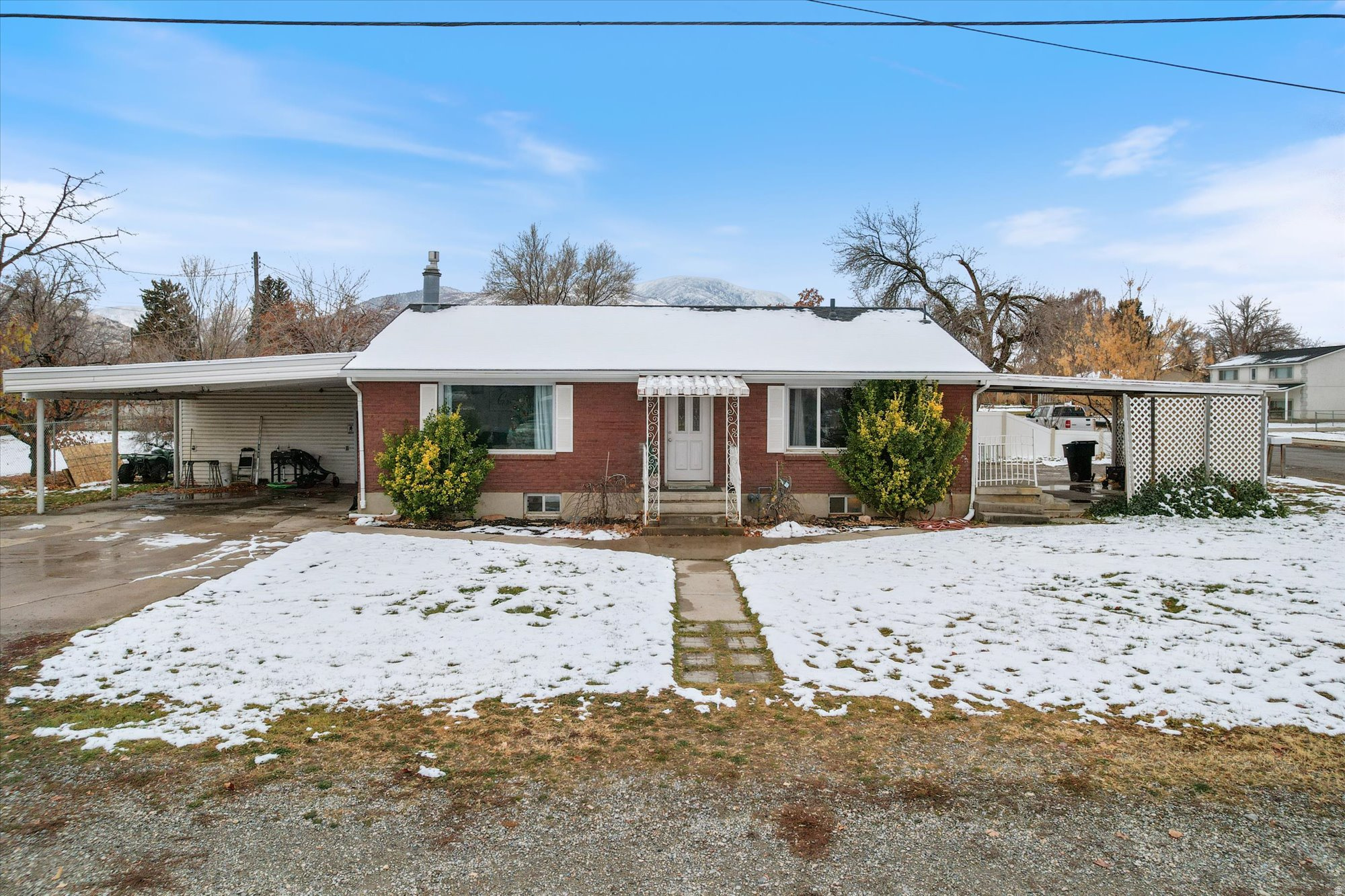 View of front of property with brick siding, an attached carport, concrete driveway, and a chimney