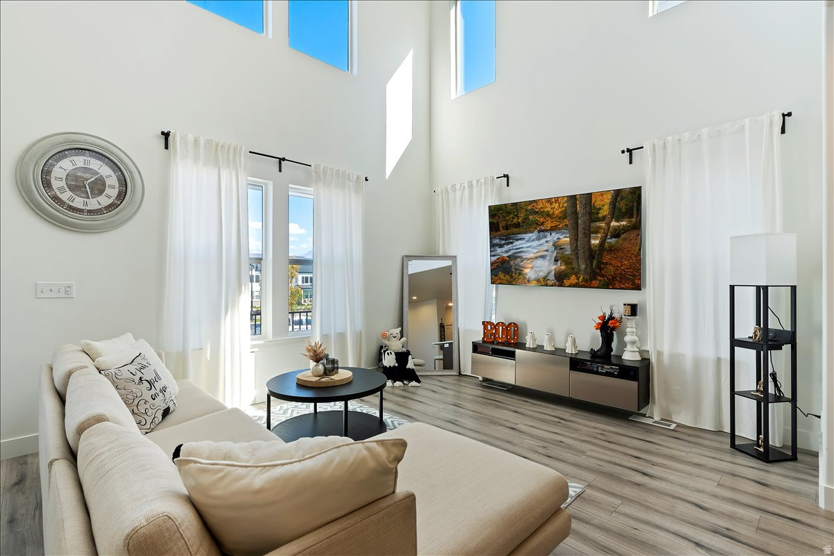 Living room with light wood-style floors and a high ceiling