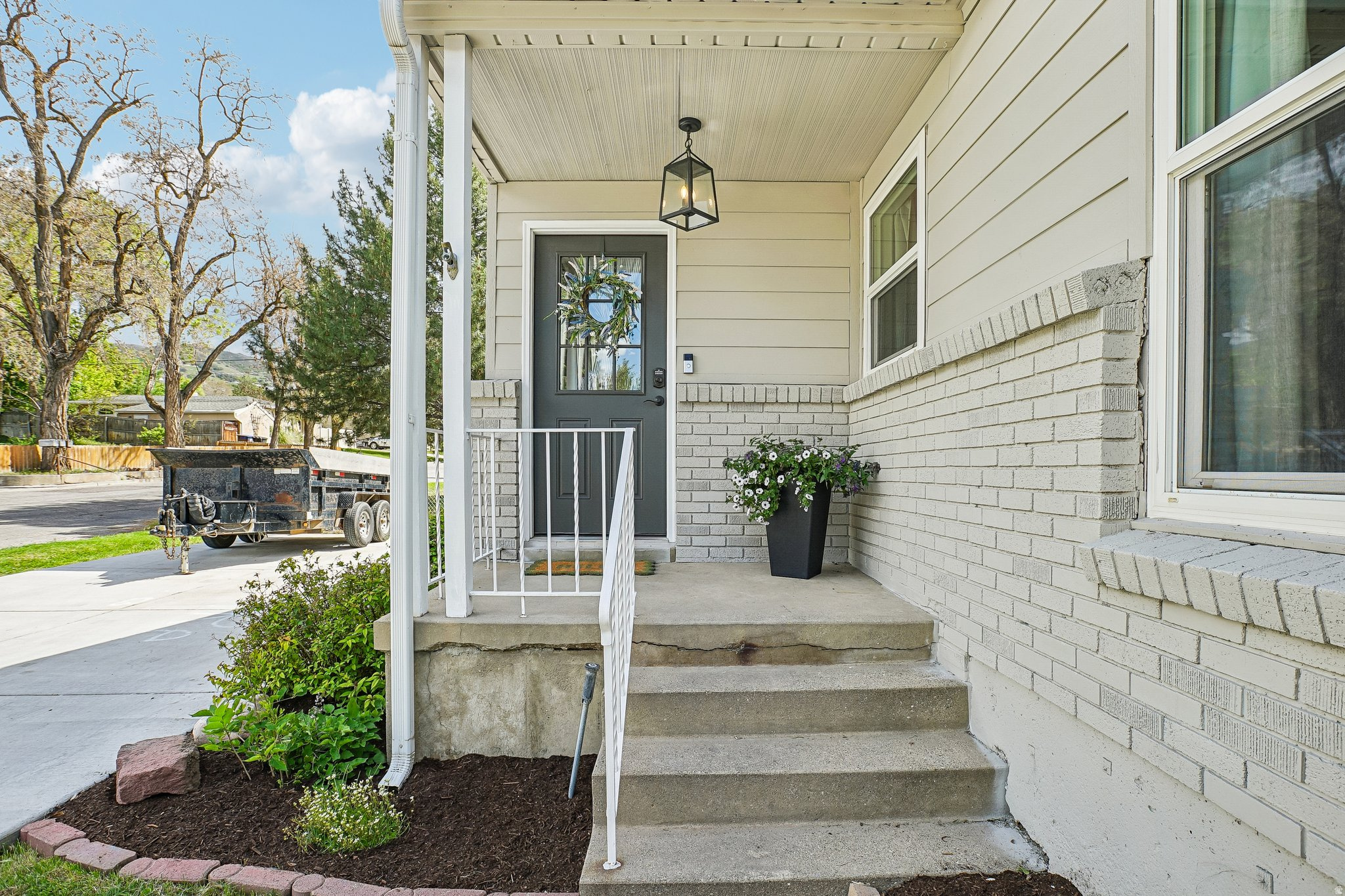 Inviting front entry featuring a covered porch, concrete steps, and white metal railings