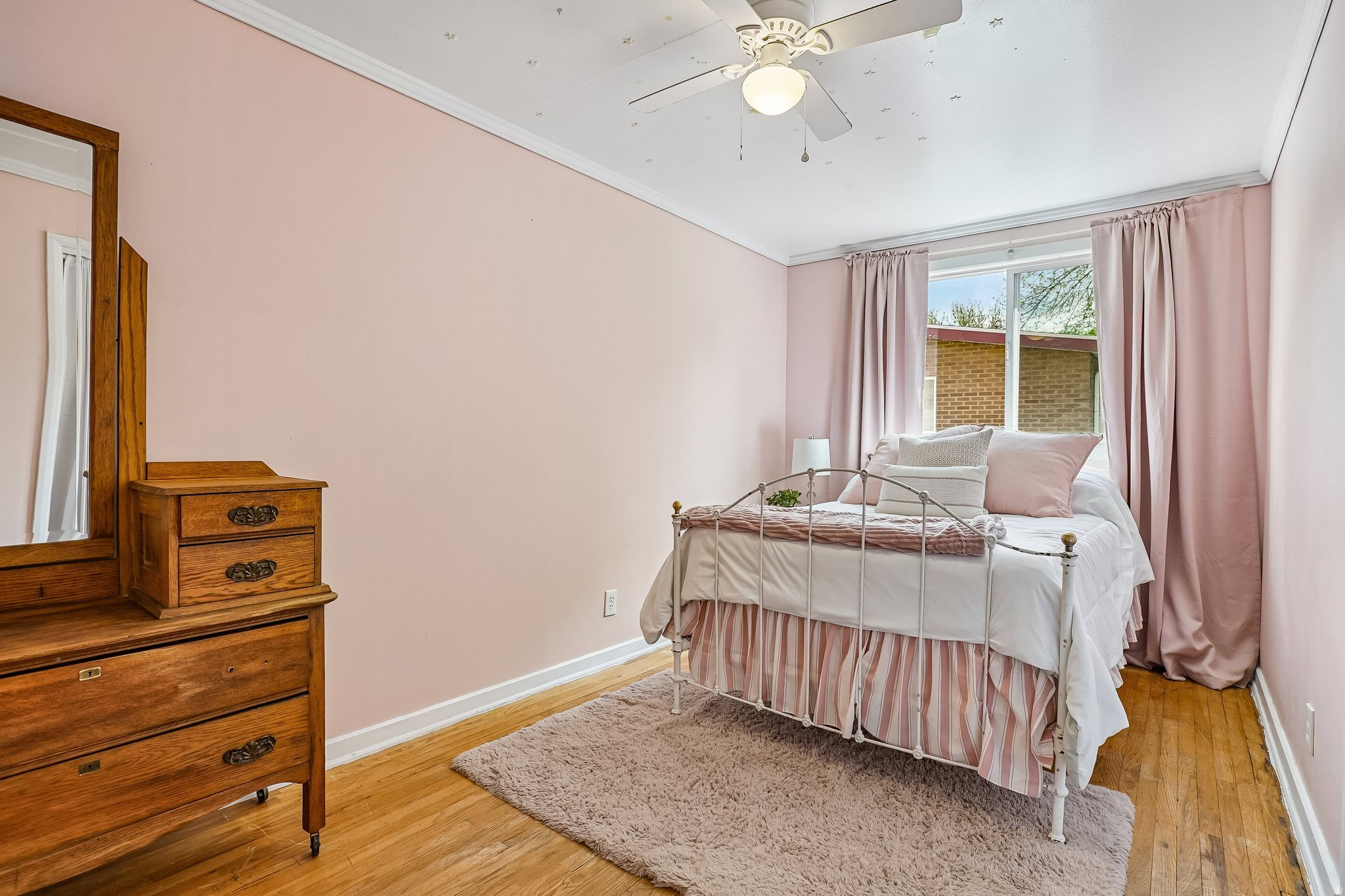 Bedroom featuring wood-finish flooring, a ceiling fan with integrated lighting, and a window with a white frame