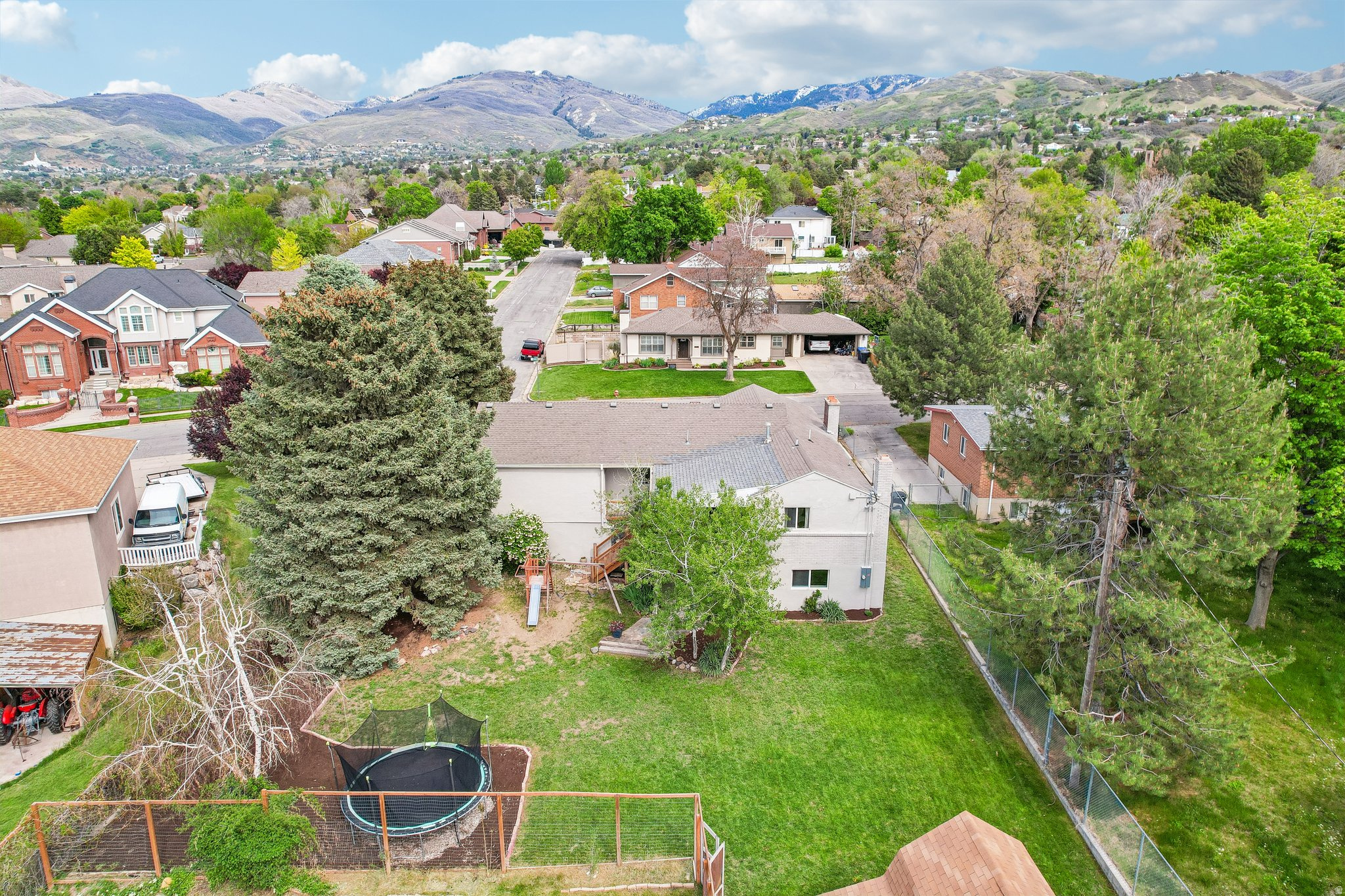 Expansive backyard featuring a manicured lawn, mature trees, and mountainous terrain in the distant background