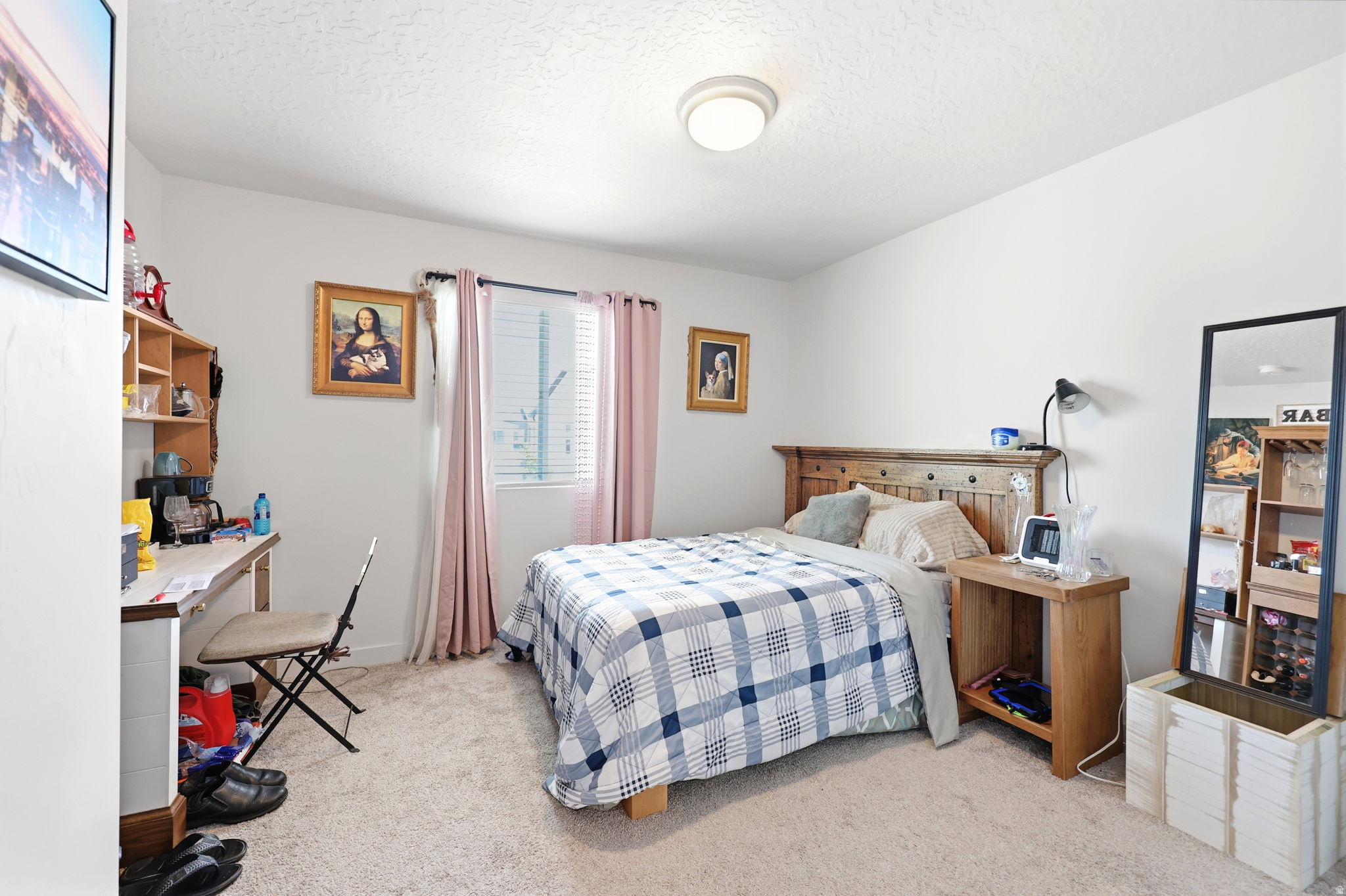 Carpeted bedroom featuring a window with blinds and pink drapes, a ceiling-mounted light fixture, and light-colored walls