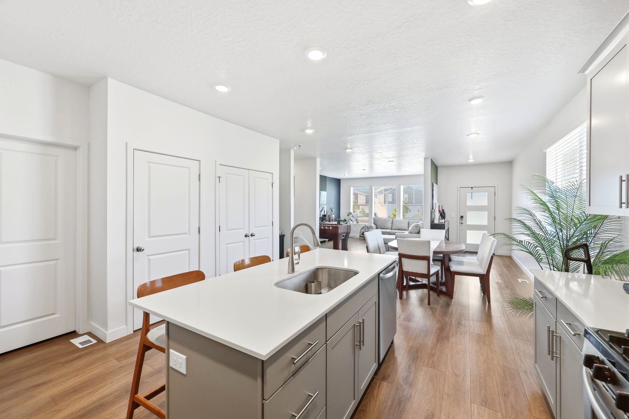 Kitchen island with integrated stainless steel sink, contemporary cabinetry, and wood-finish flooring