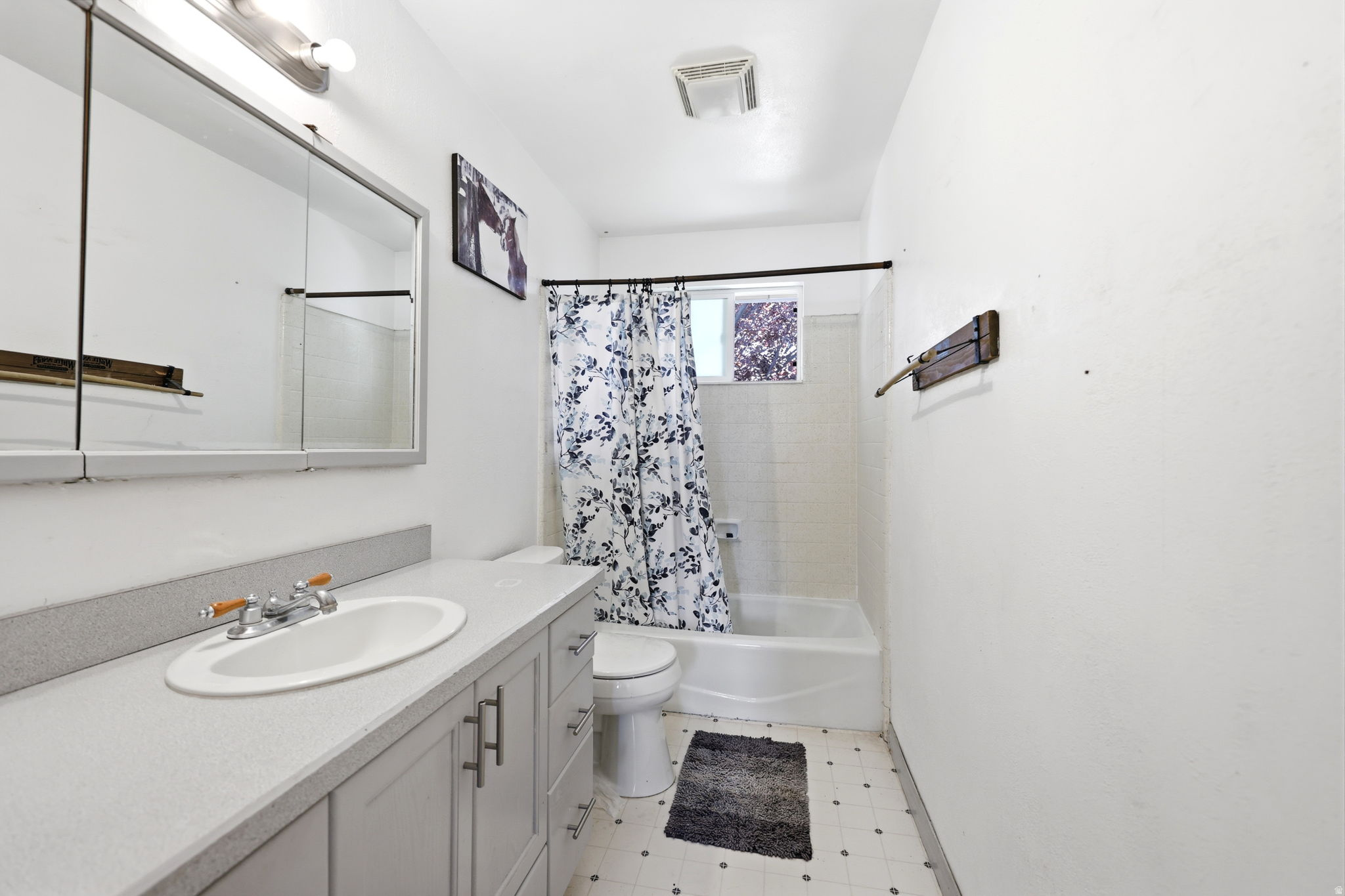 Bathroom featuring a vanity with a white oval sink, chrome faucet, and gray cabinetry