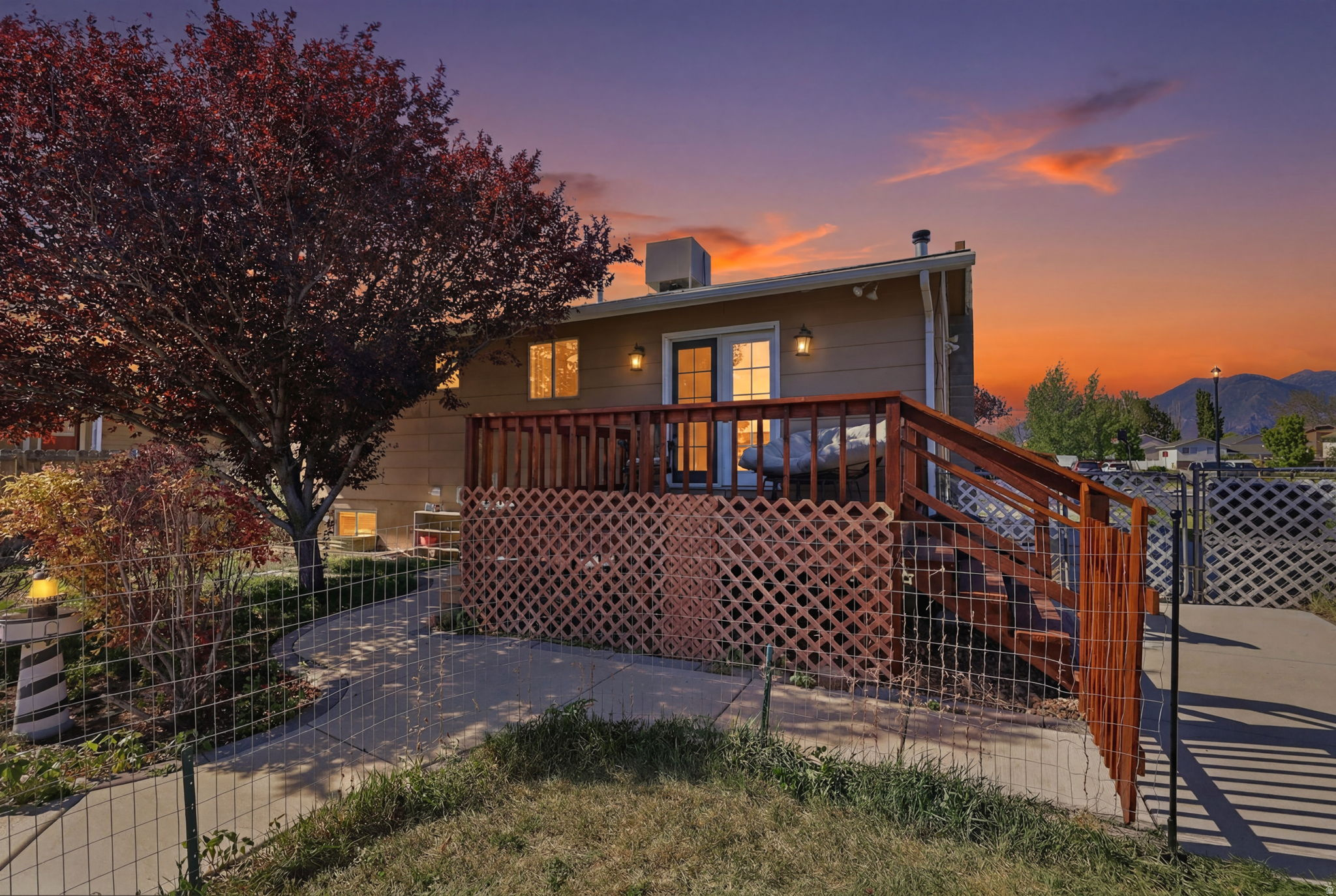 Rear exterior featuring a spacious wood deck, privacy lattice, and a concrete patio