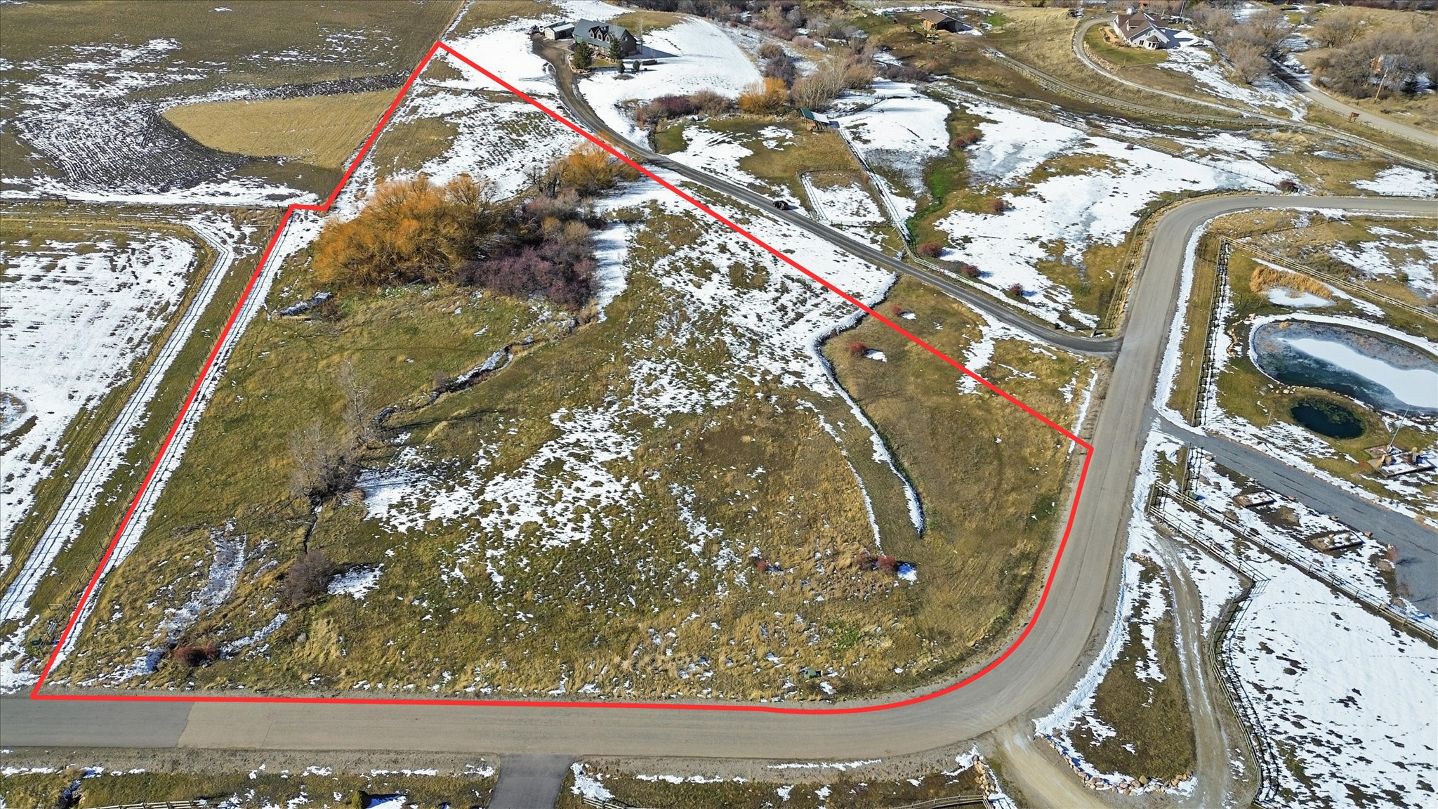 Expansive land parcel featuring partial snow cover, natural terrain, and established road access