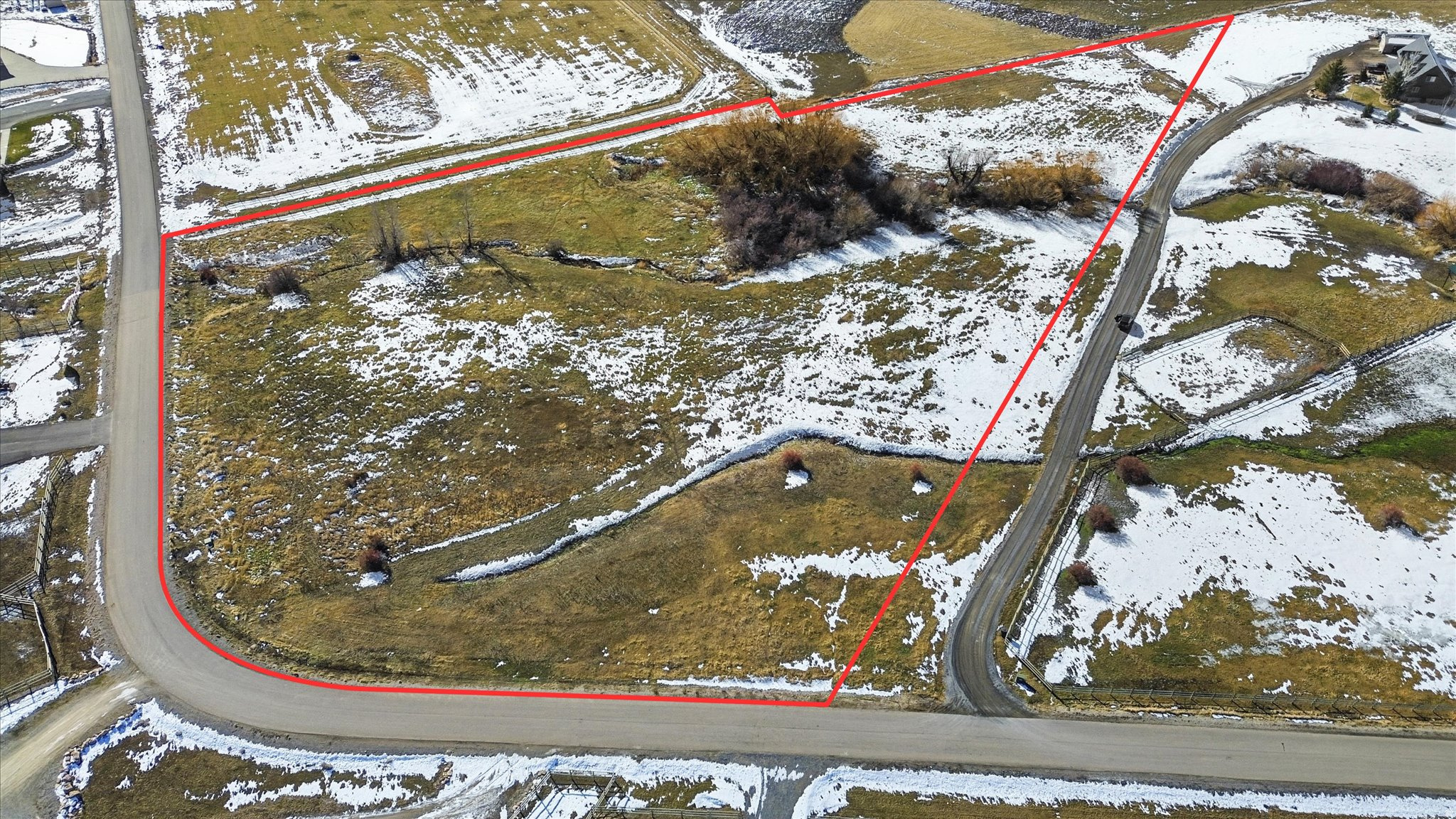 Expansive land parcel featuring existing road frontage and gently sloping terrain