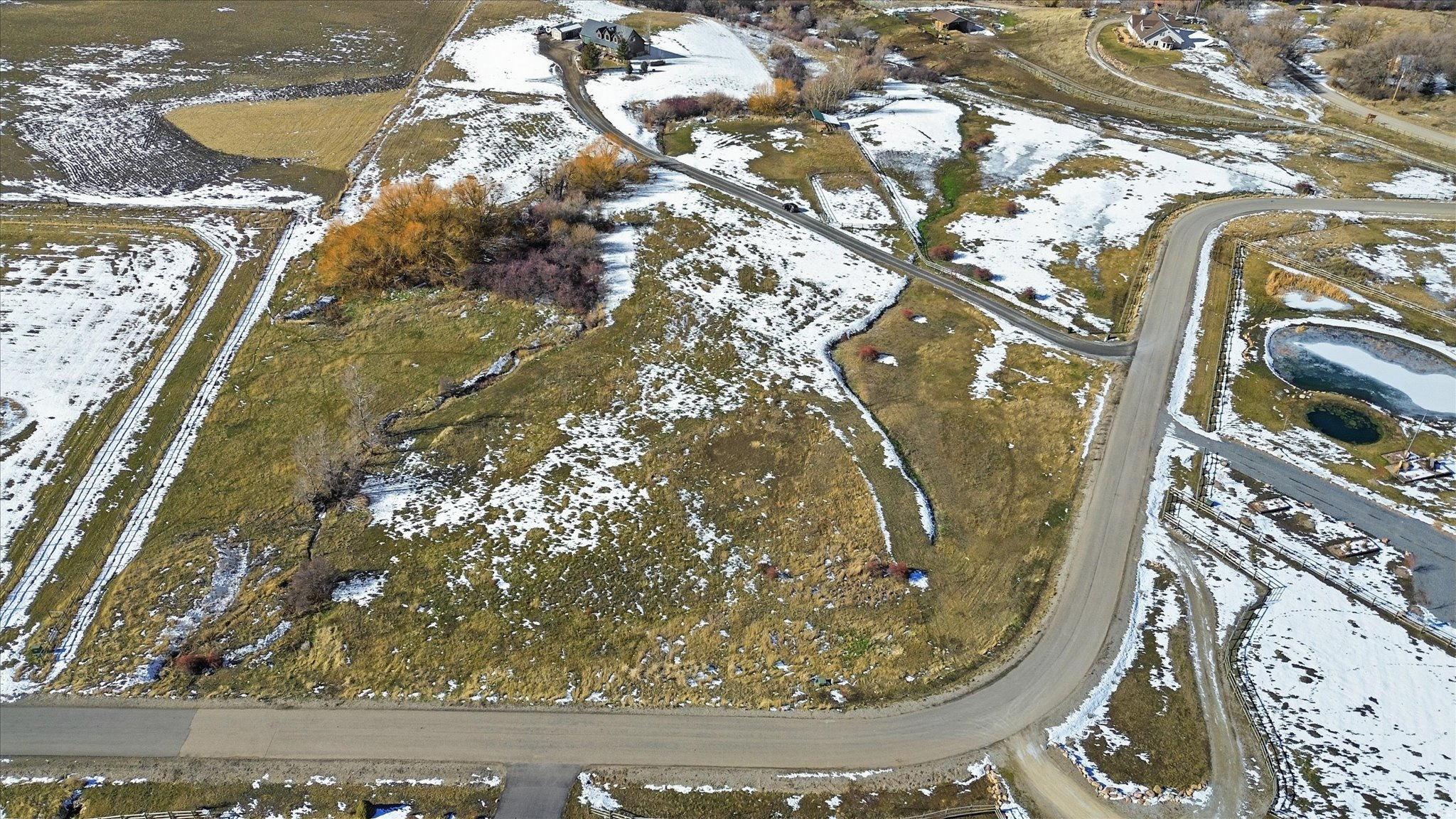 Expansive land parcel with surrounding agricultural fields, mature trees, and a visible road network