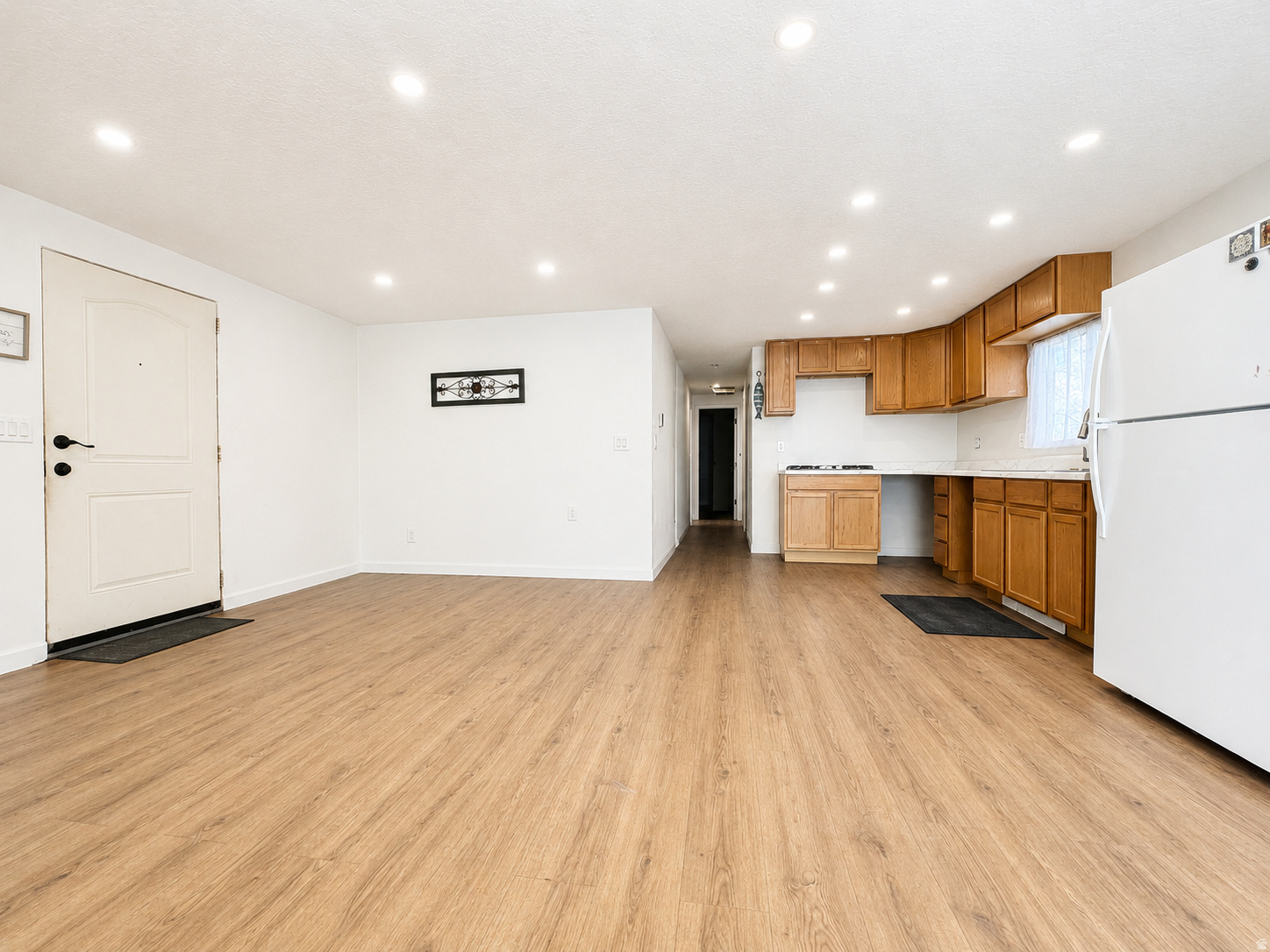 Open concept living area featuring wood-finish flooring, recessed lighting, and a white entry door