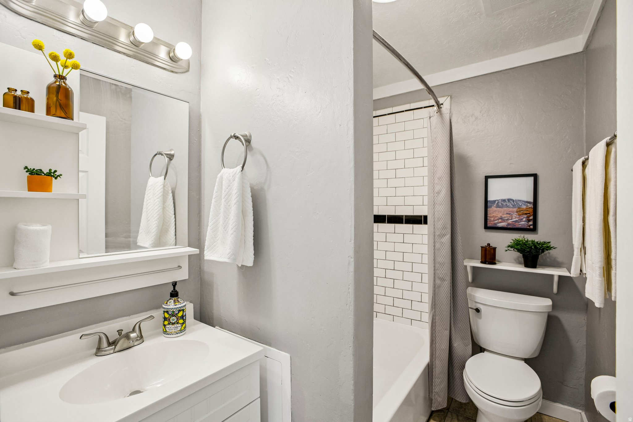 Bathroom featuring a white vanity with integrated sink, brushed nickel faucet, and a wall-mounted mirror