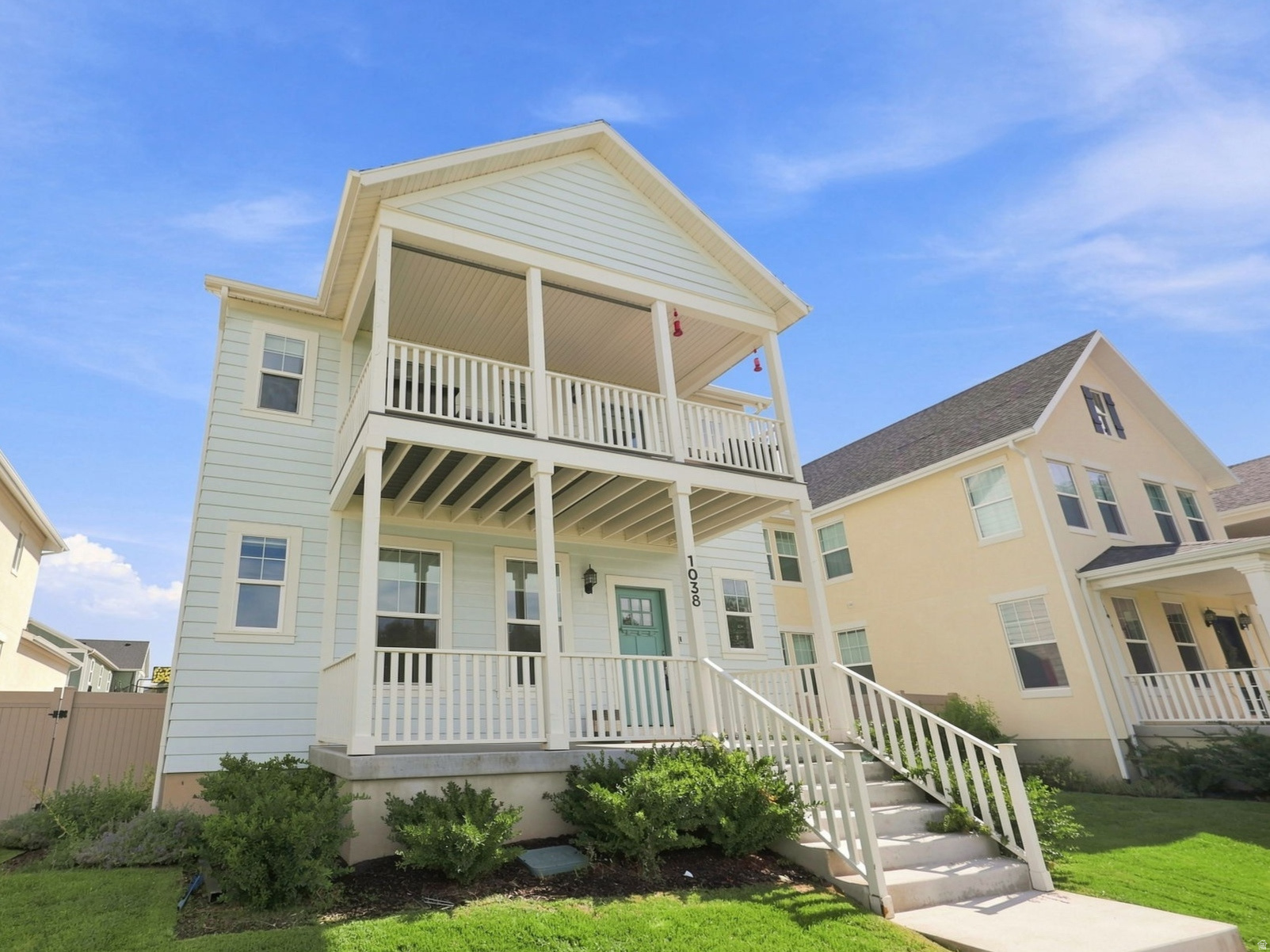 Two-story residence featuring light blue siding, a covered front porch, and a second-story balcony