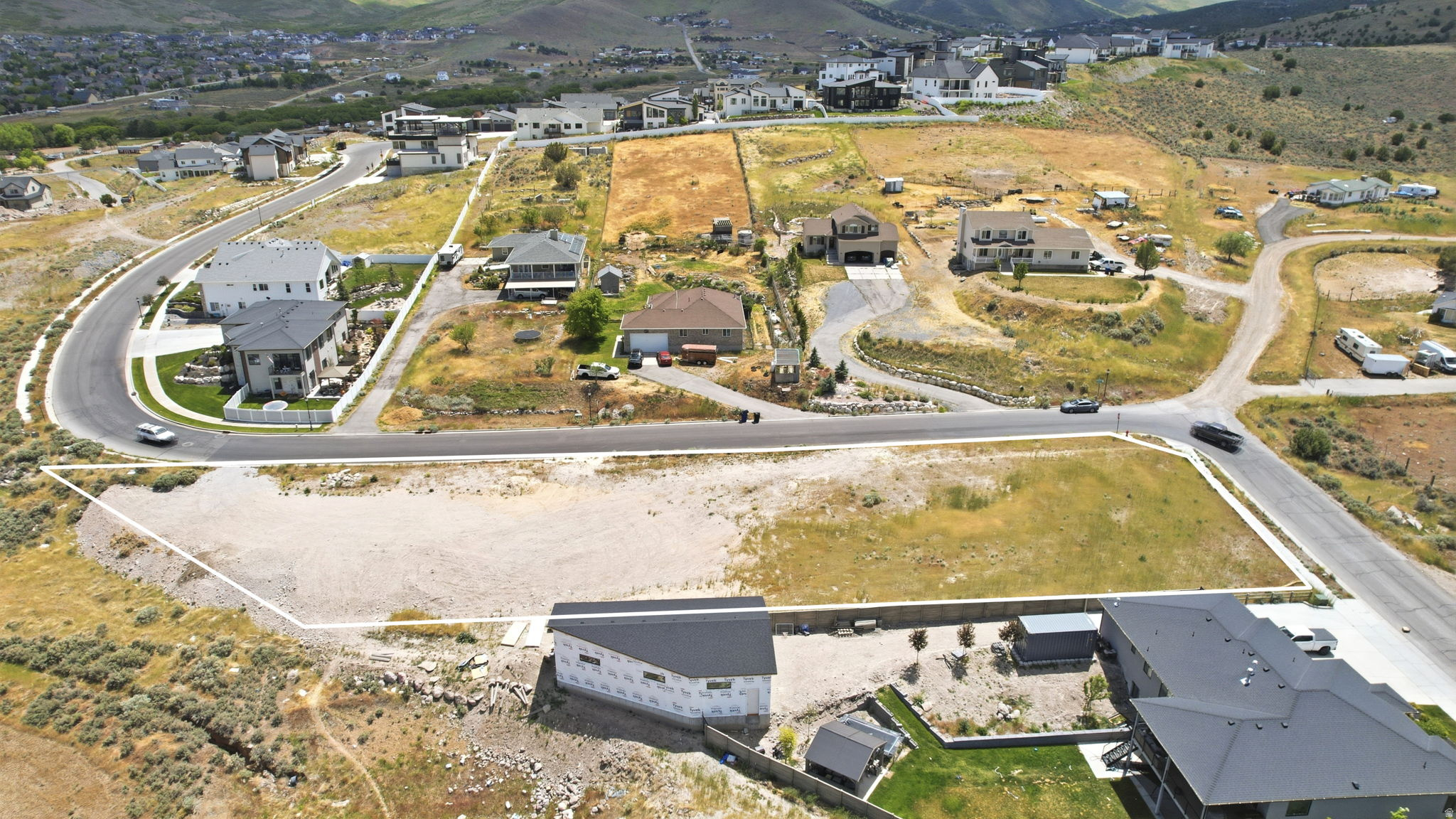 Cleared building lot positioned at a road intersection, featuring established roads and utility access