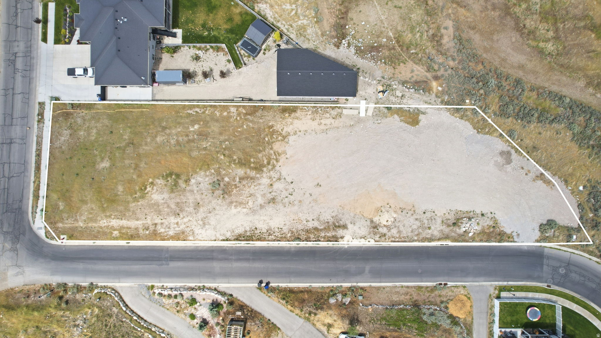Expansive corner lot featuring a partial grass area, a partial graded area, and paved street frontage