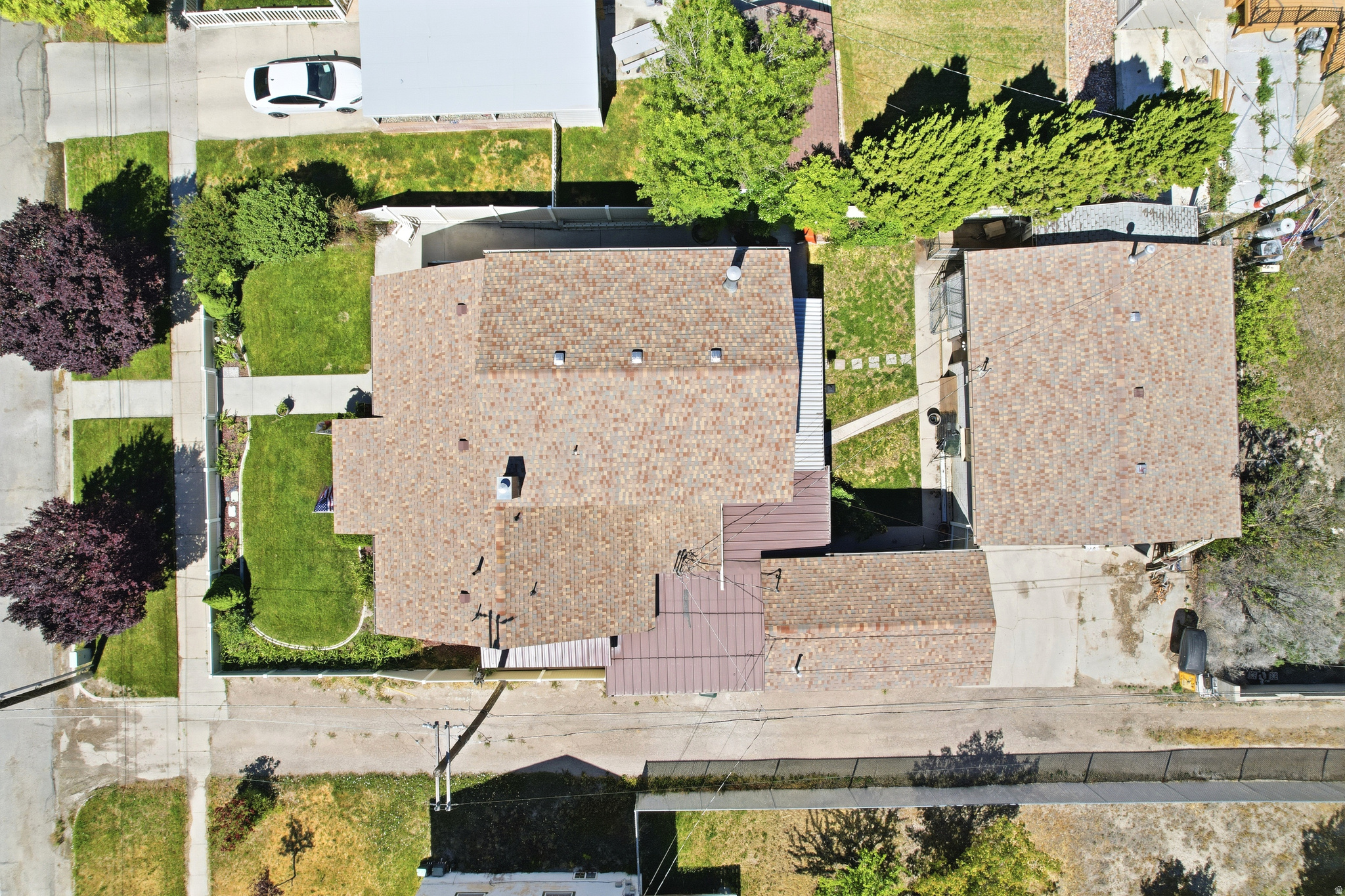 Aerial perspective highlighting the property with its primary structure, detached garage, and surrounding green spaces