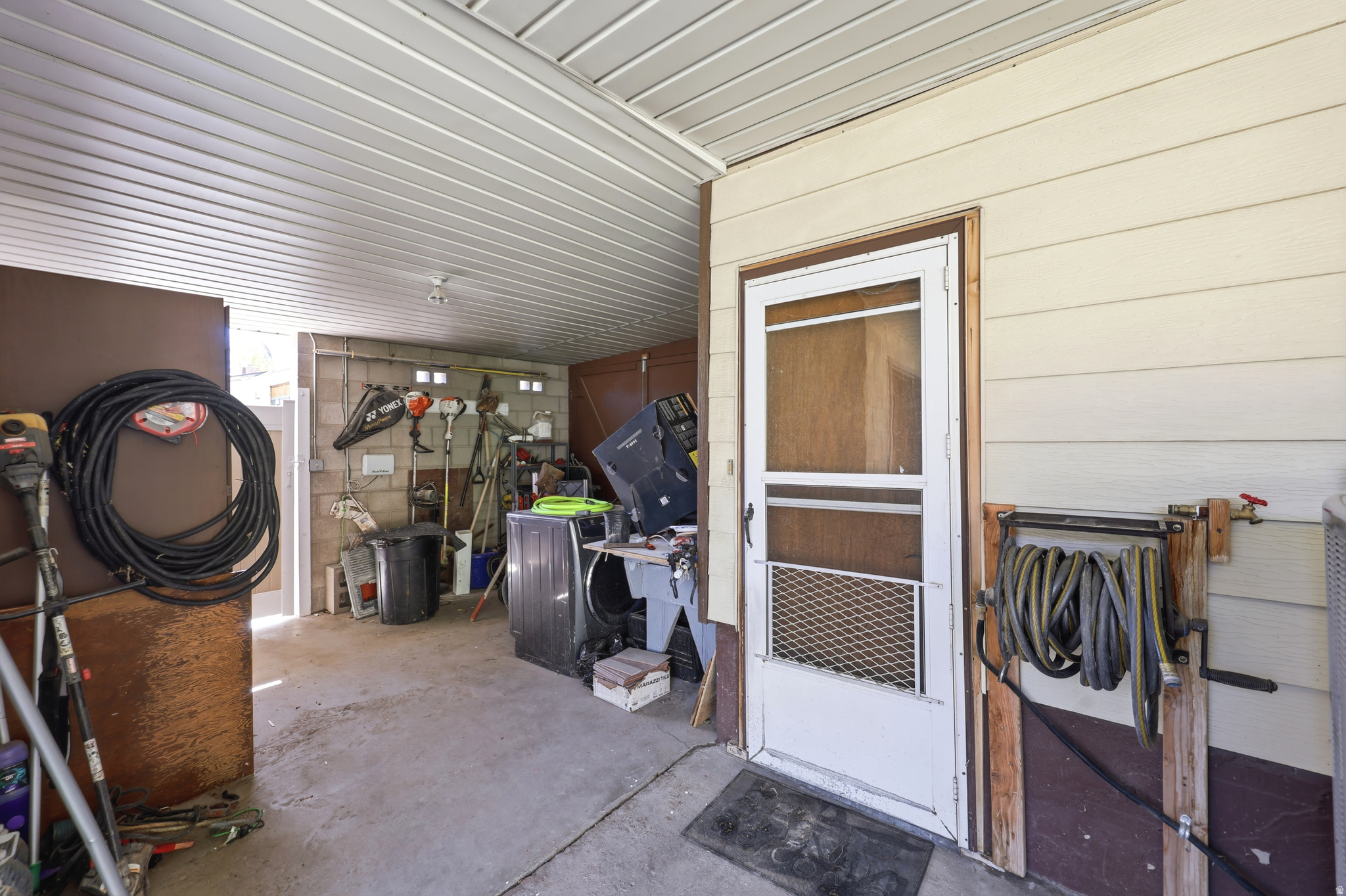 Covered patio area with concrete flooring, slatted ceiling, and exterior siding
