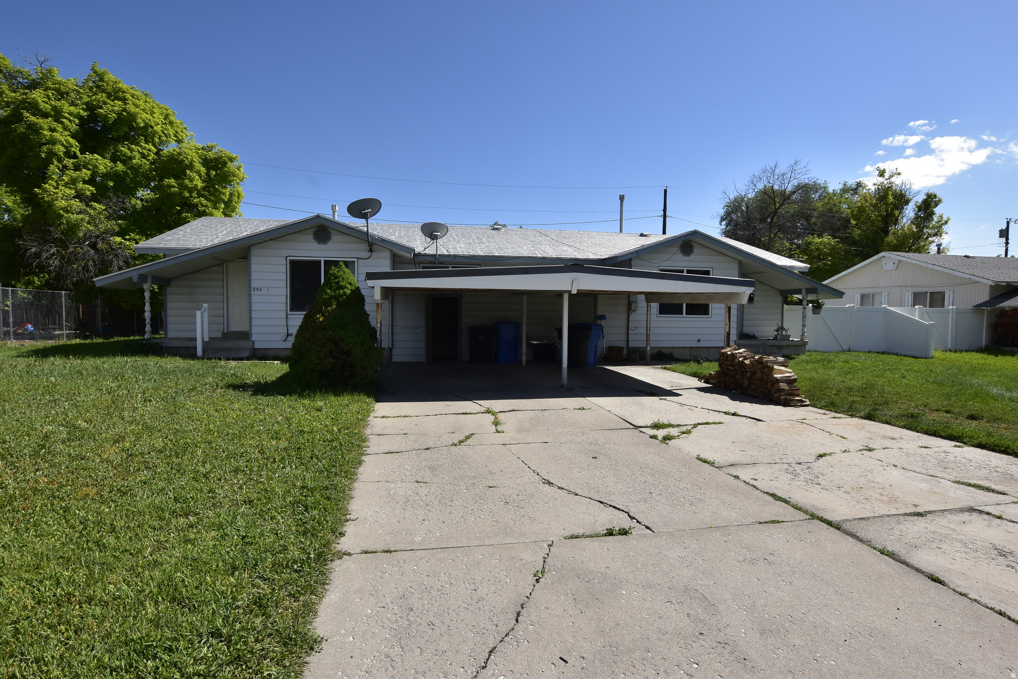 Ranch-style exterior featuring a covered carport, concrete driveway, and front lawn