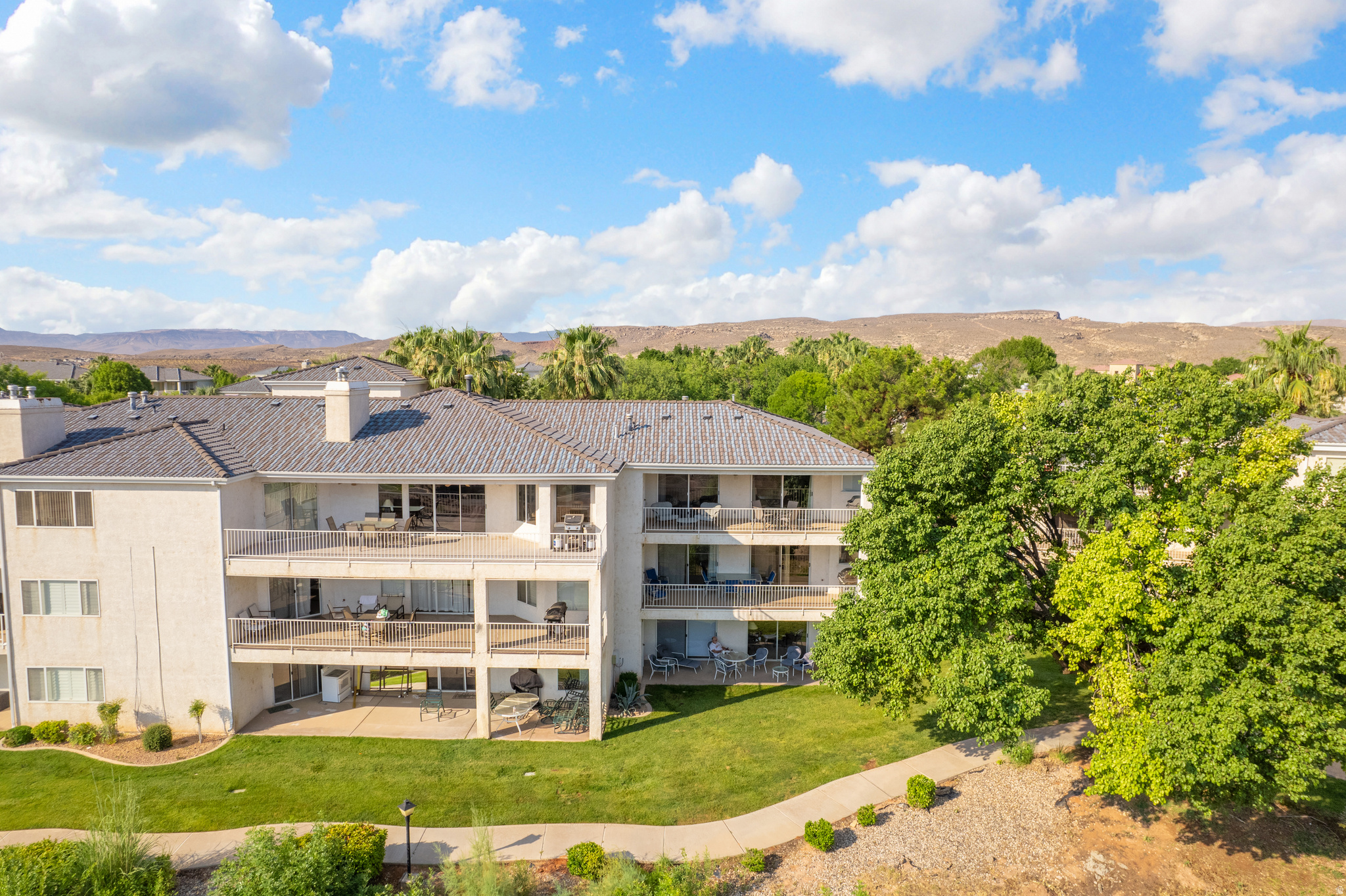 Multi-level property featuring private balconies, individual patios, and a manicured lawn