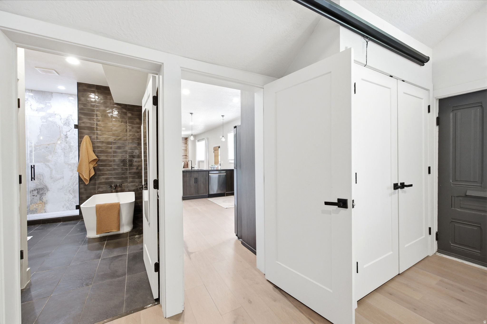 Contemporary bathroom featuring a freestanding tub, dark subway tile accent wall, and a spacious glass-enclosed shower with large format marble-patterned tile